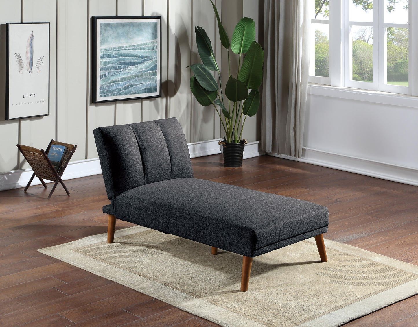 Dark gray fabric chaise lounge with tufted back and wooden legs on a rug