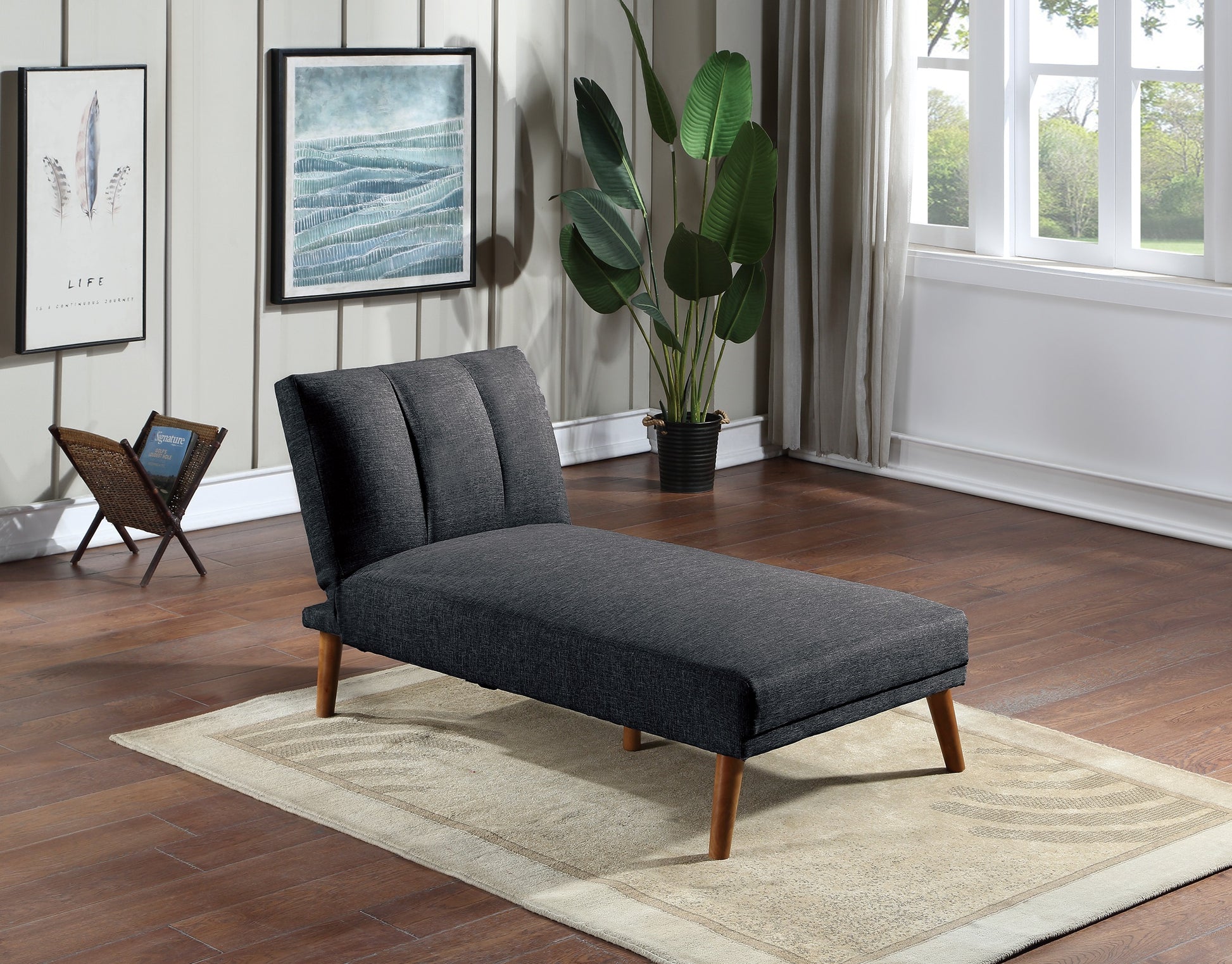 Dark gray fabric chaise lounge with tufted back and wooden legs on a rug