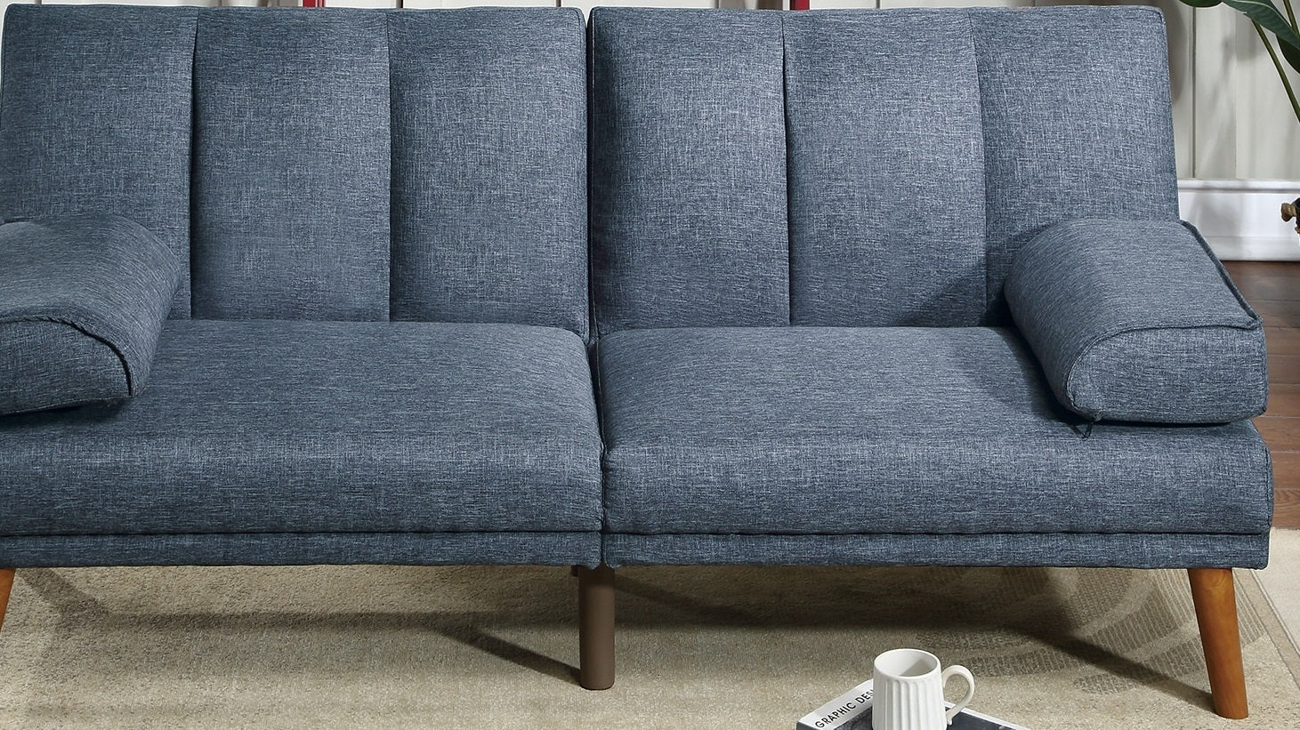 Blue fabric sofa with tufted backrest and cylindrical throw pillows