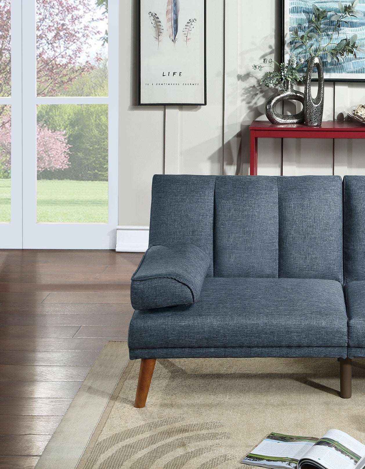 Blue linen upholstered futon sofa with wooden legs and decorative pillow