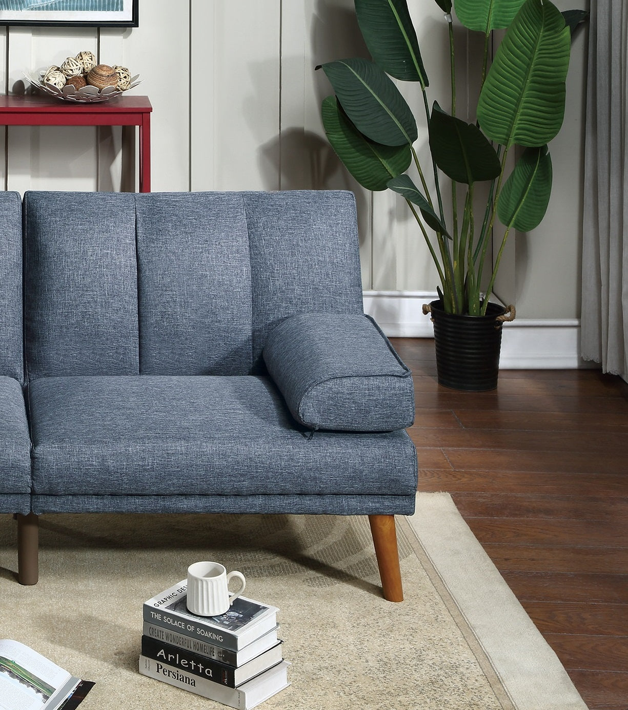 Blue upholstered sofa with tufted back cushions and wooden legs