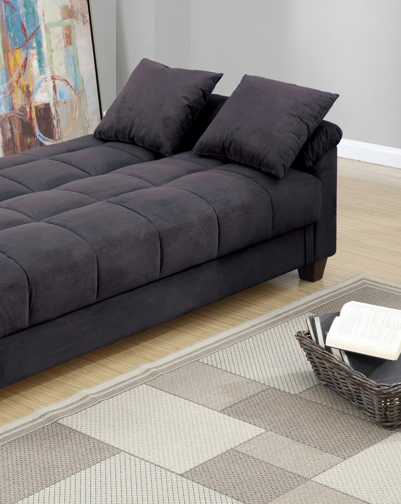 Dark gray velvet tufted futon sofa with two plush throw pillows ideal for small spaces