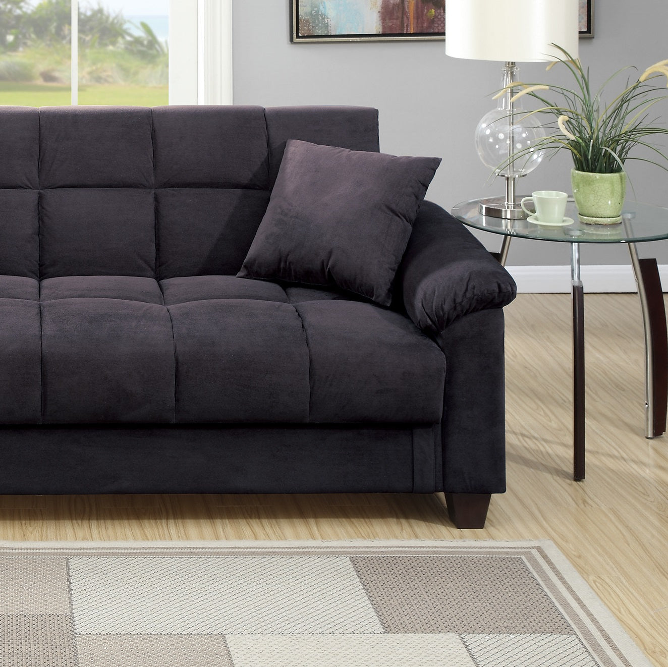 Dark charcoal sofa with tufted cushions and a single accent pillow