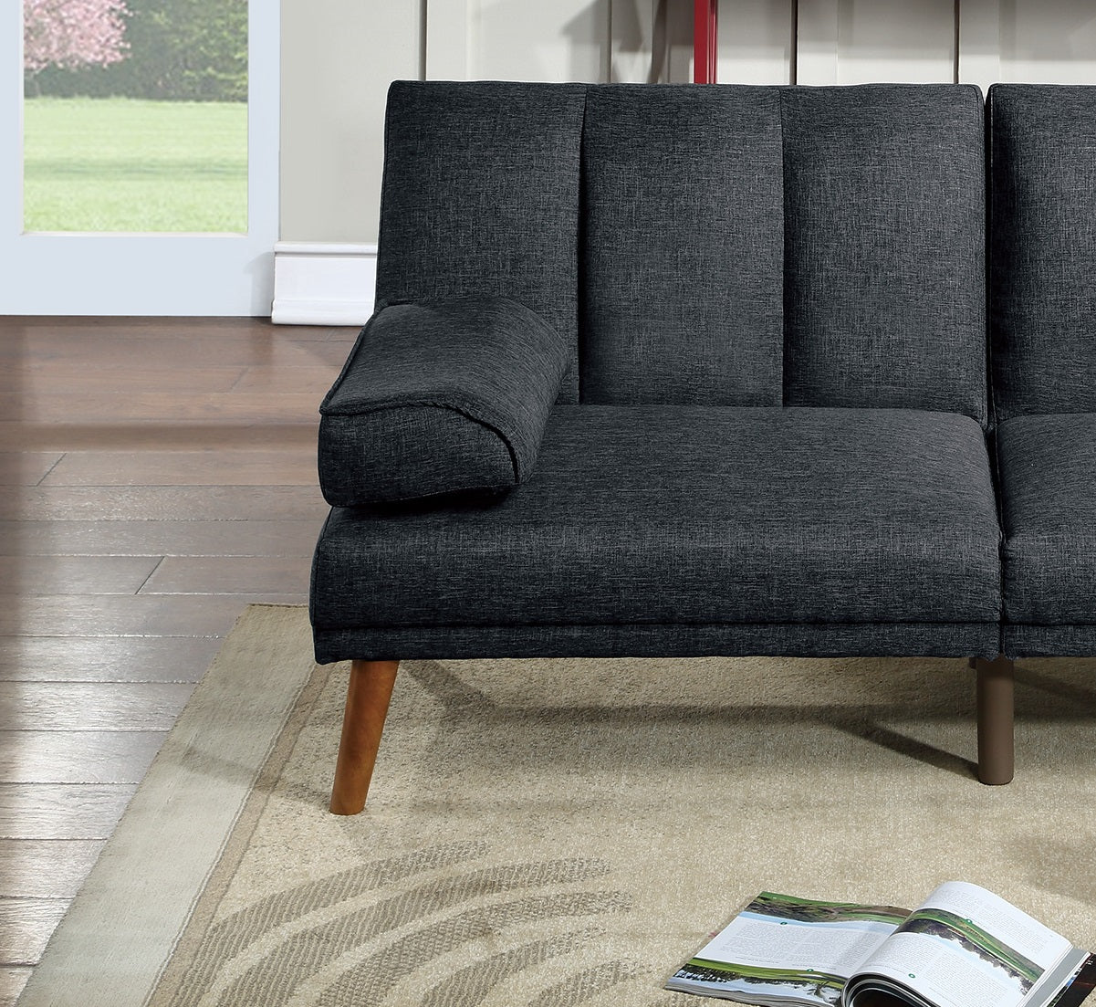 Dark gray upholstered sofa with a detached bolster pillow and tapered wooden legs