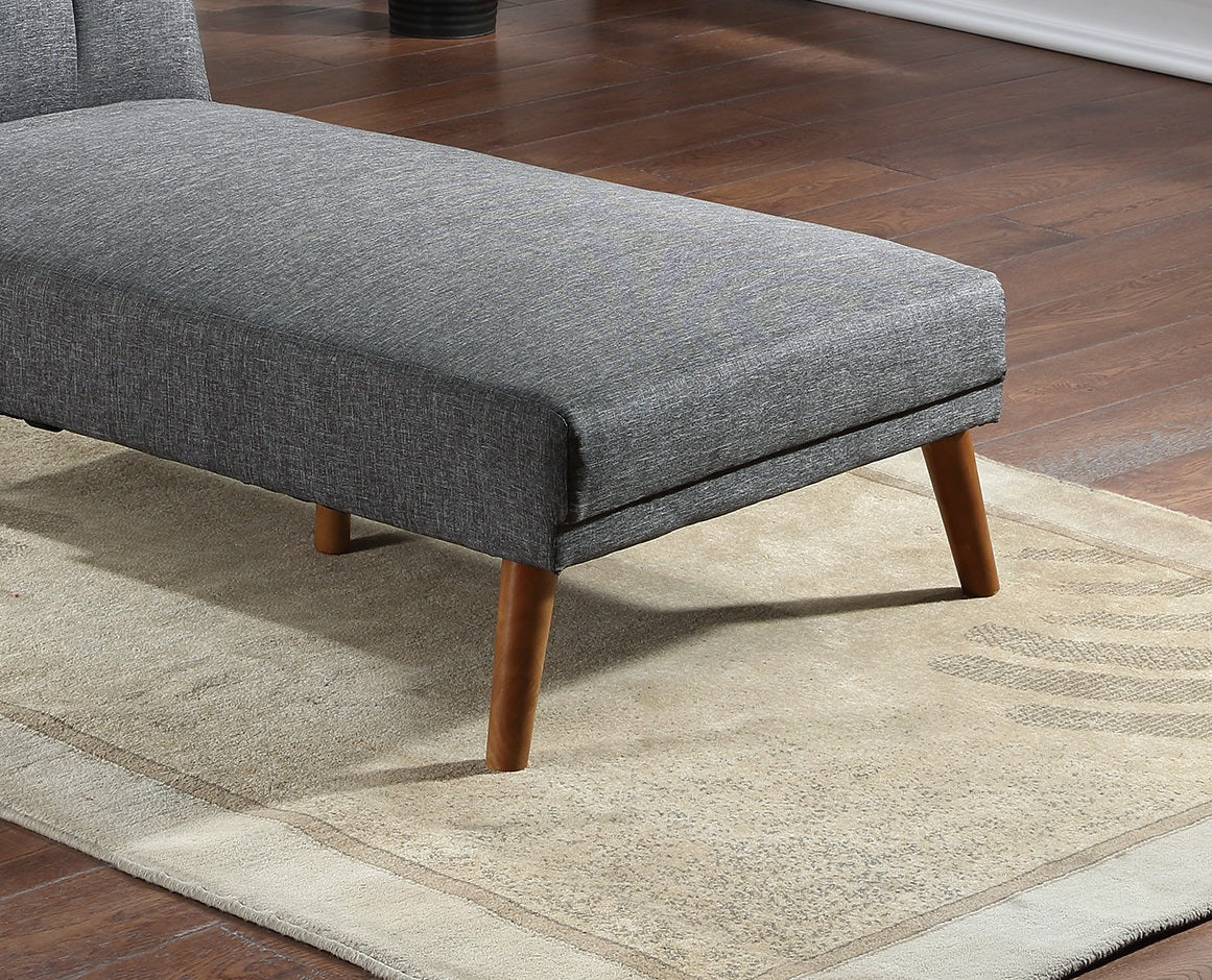 Grey upholstered chaise lounge with wooden legs on a patterned rug