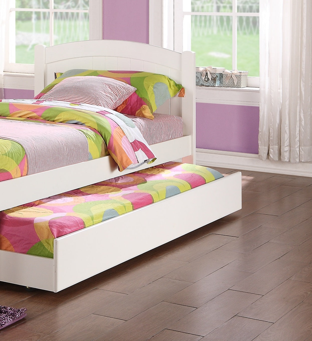White twin bed frame with colorful bedding and trundle drawer