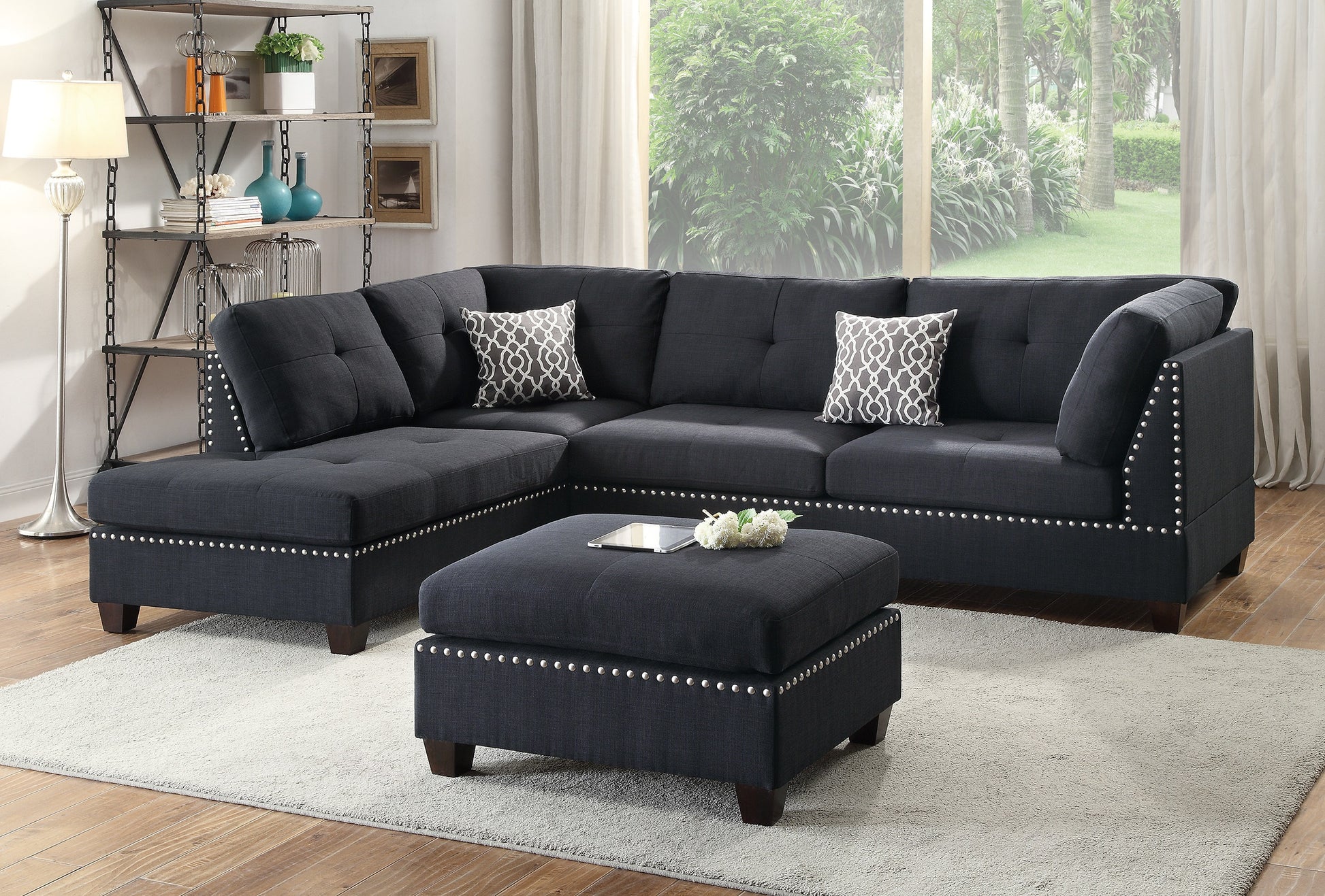 Dark gray tufted sectional sofa with studded trim and patterned pillows