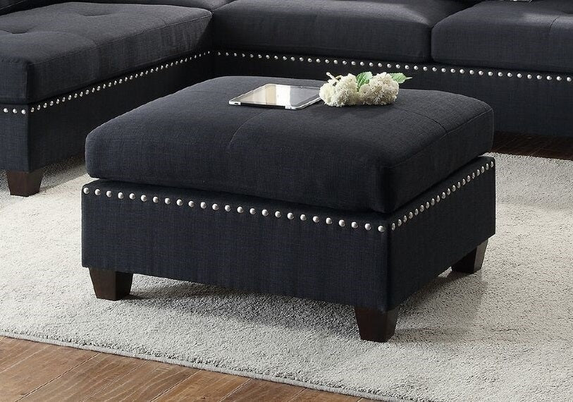 Square navy blue fabric ottoman with silver nailhead trim and dark wood legs