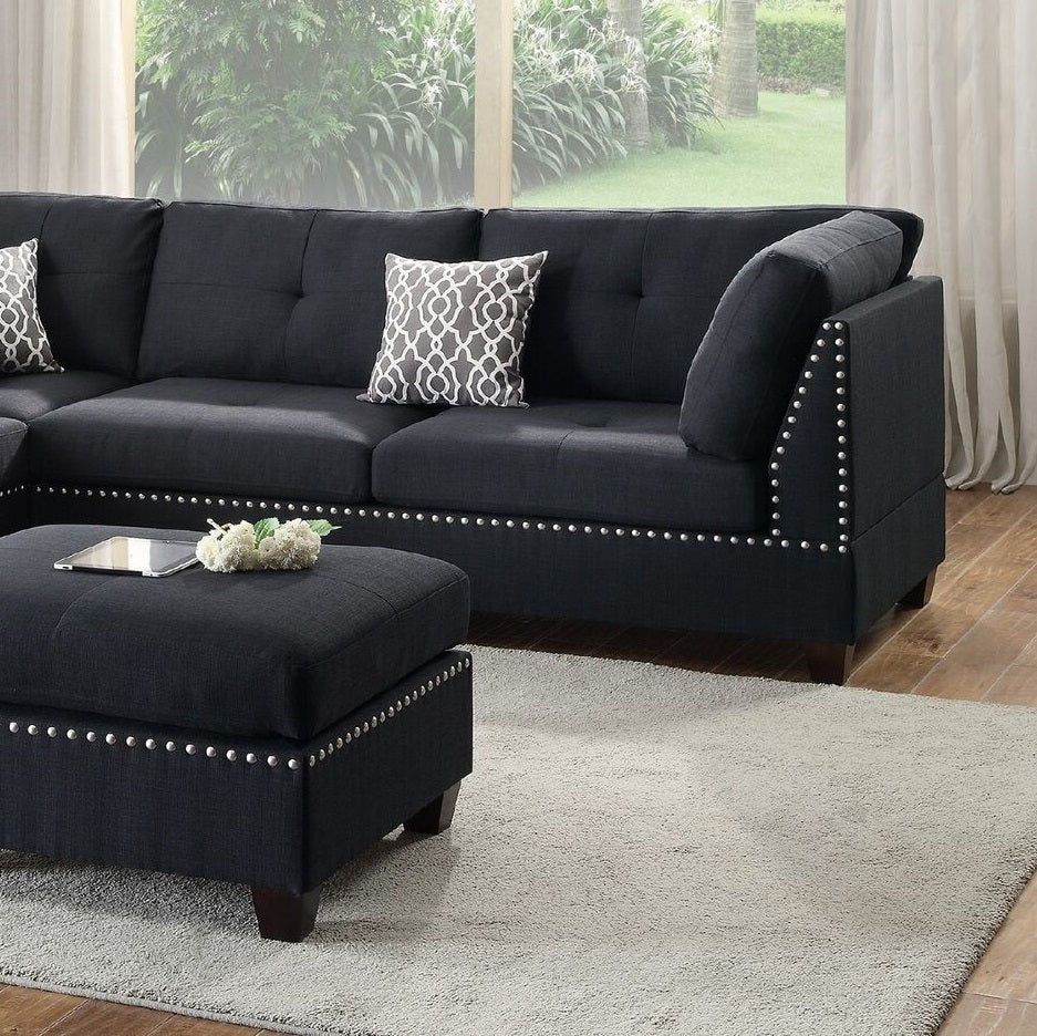 Dark gray upholstered sectional sofa with silver nailhead trim and decorative pillows