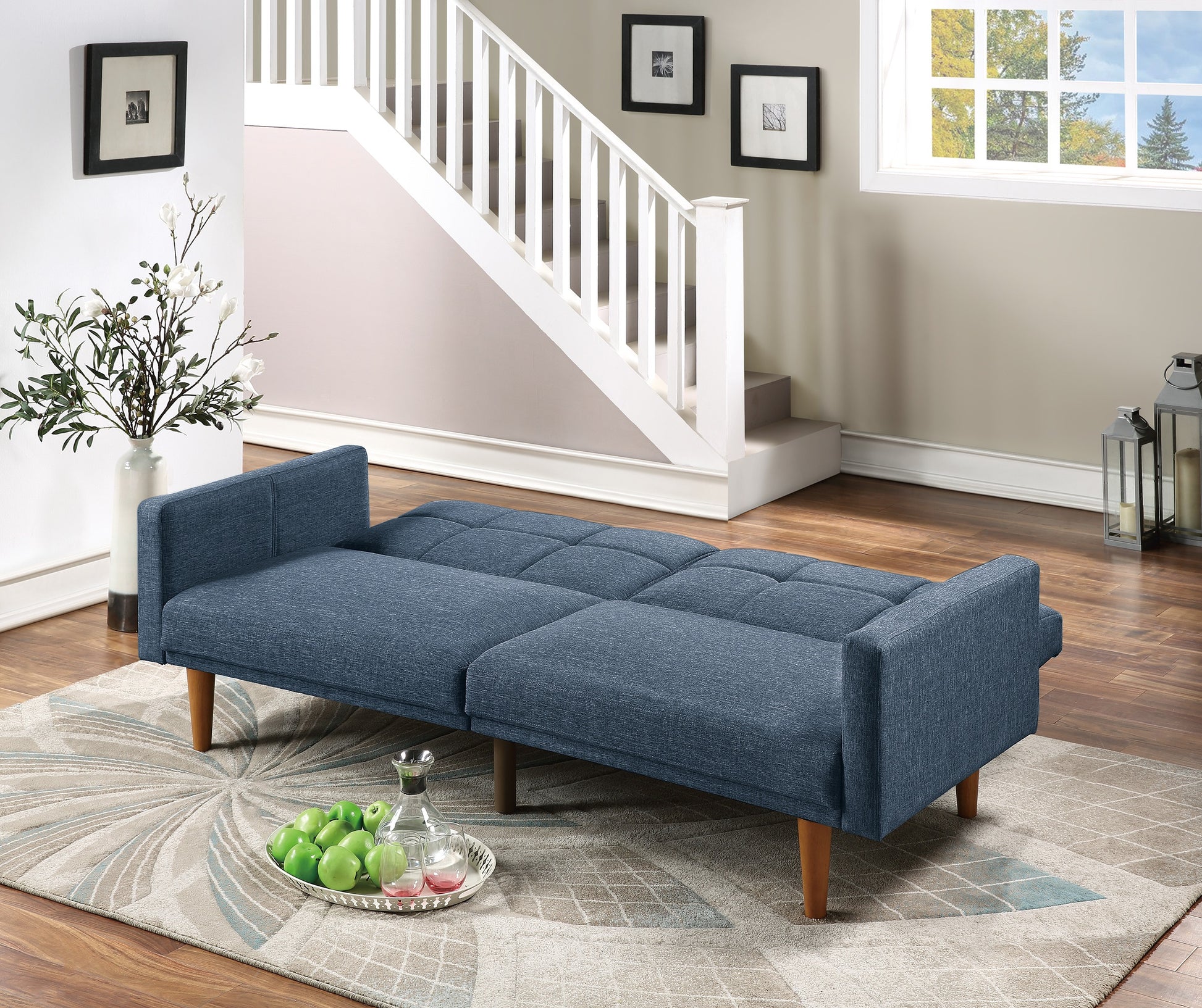 Blue upholstered futon sofa with tufted seat and wooden legs