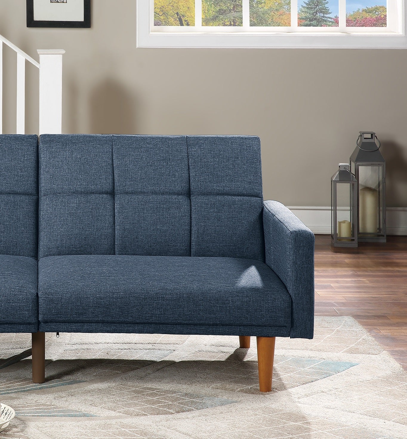 Blue upholstered sofa with tufted back cushions and wooden legs