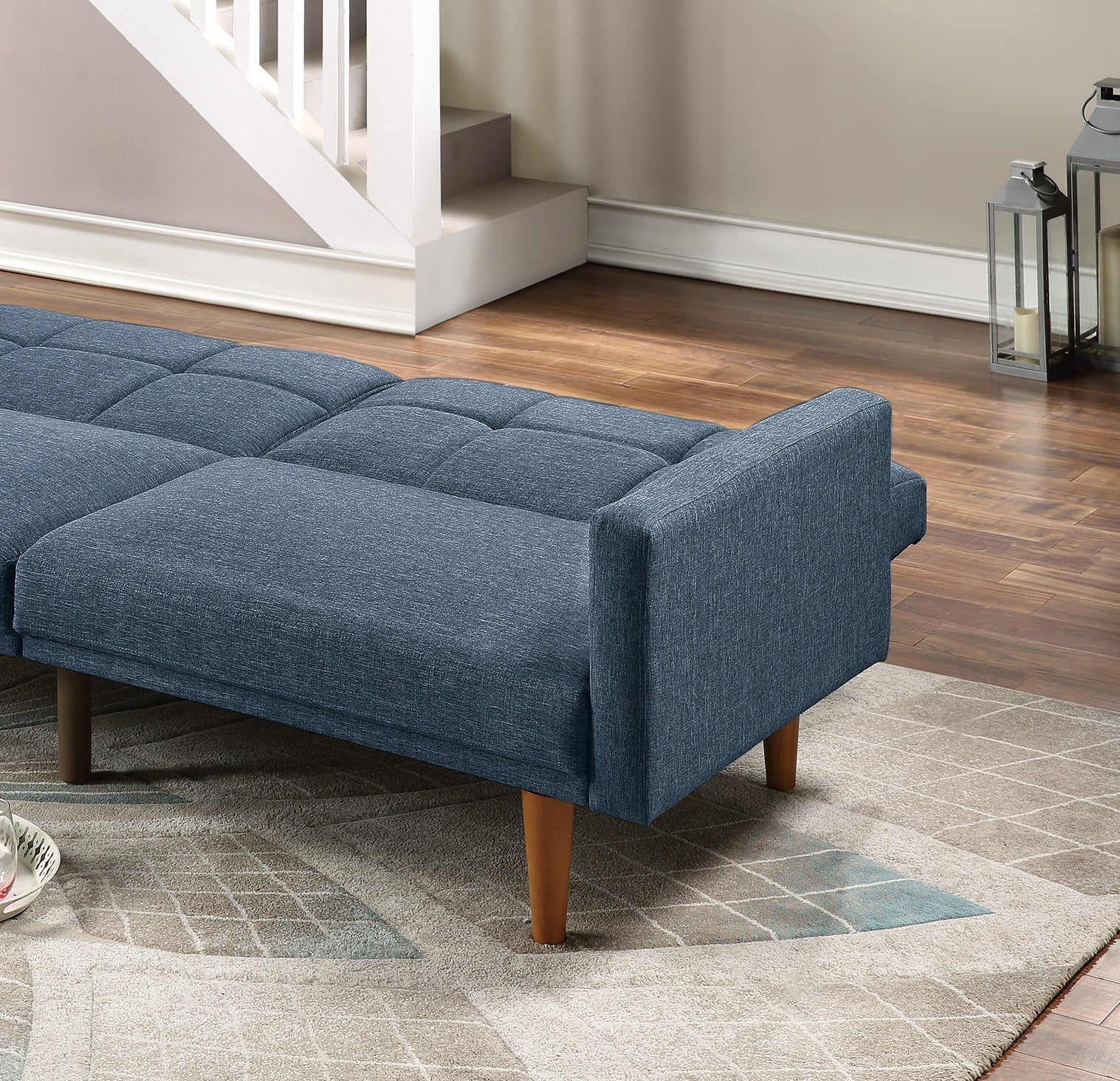 Blue upholstered futon with tufted seat cushions and wooden legs