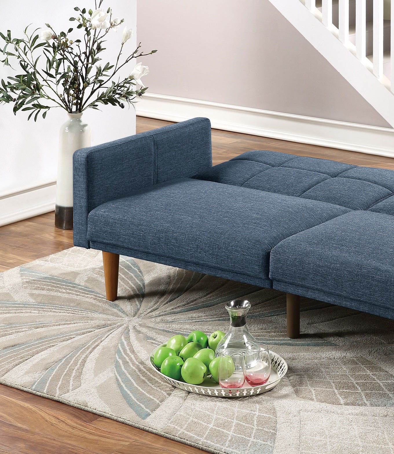 Modern blue fabric futon sofa with wooden legs and tufted seating