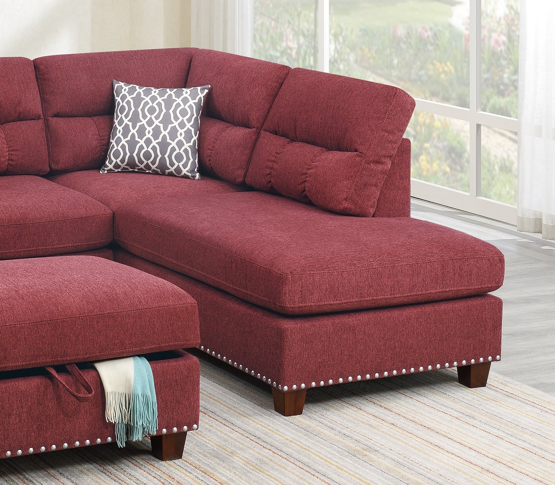 Deep red fabric sectional sofa with tufted back cushions and a decorative throw pillow