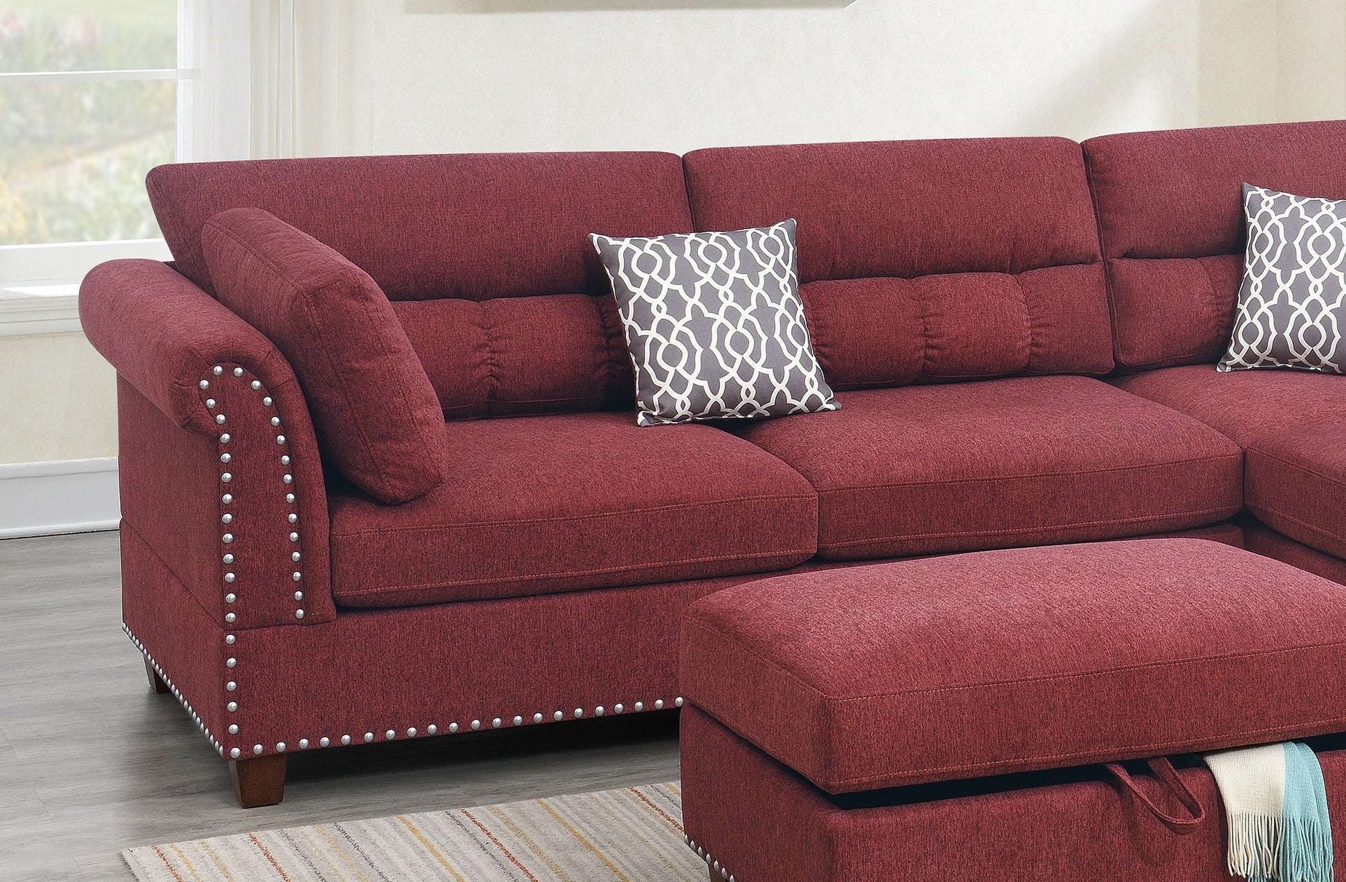 Deep red fabric sectional sofa with tufted back cushions and studded armrests