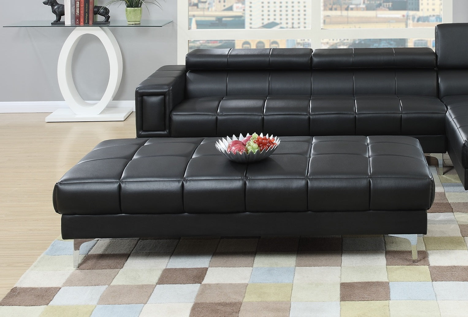 Black leather tufted sectional sofa with a matching ottoman featuring chrome legs
