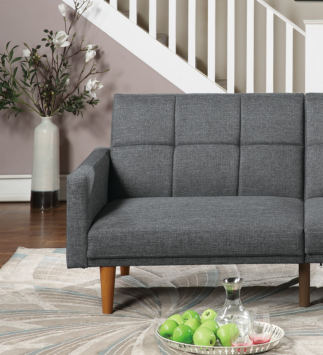 Tufted gray fabric futon sofa with tapered wooden legs perfect for small spaces