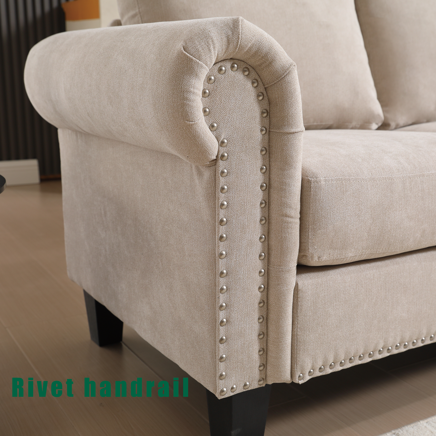 Beige linen sofa arm with decorative nailhead trim and rolled armrest