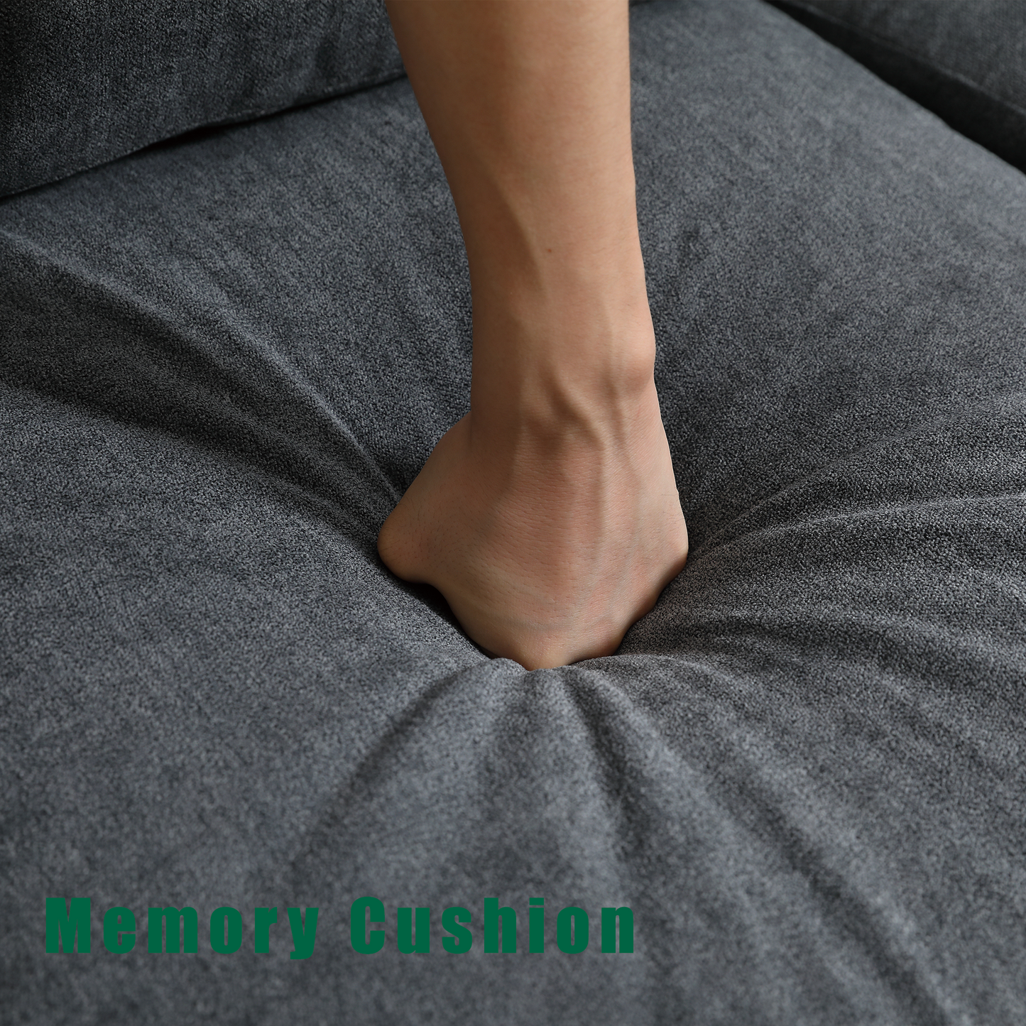 Closeup of a hand pressing into a dark grey fabric sofa cushion highlighting its memory foam comfort