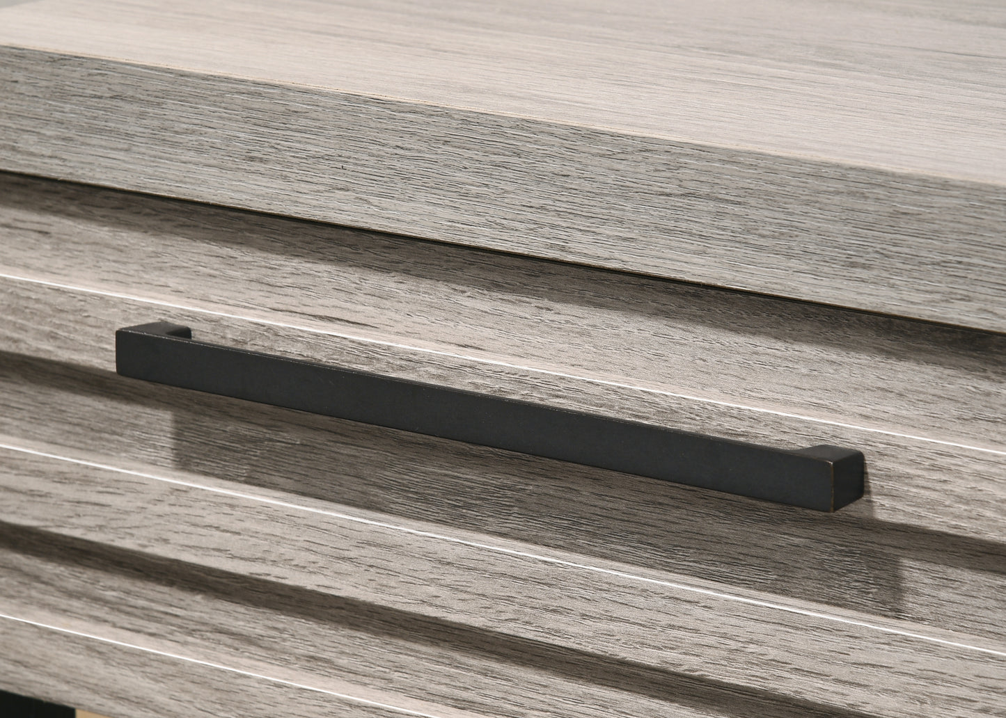 Closeup of grey wood grain texture with a dark bronze drawer pull