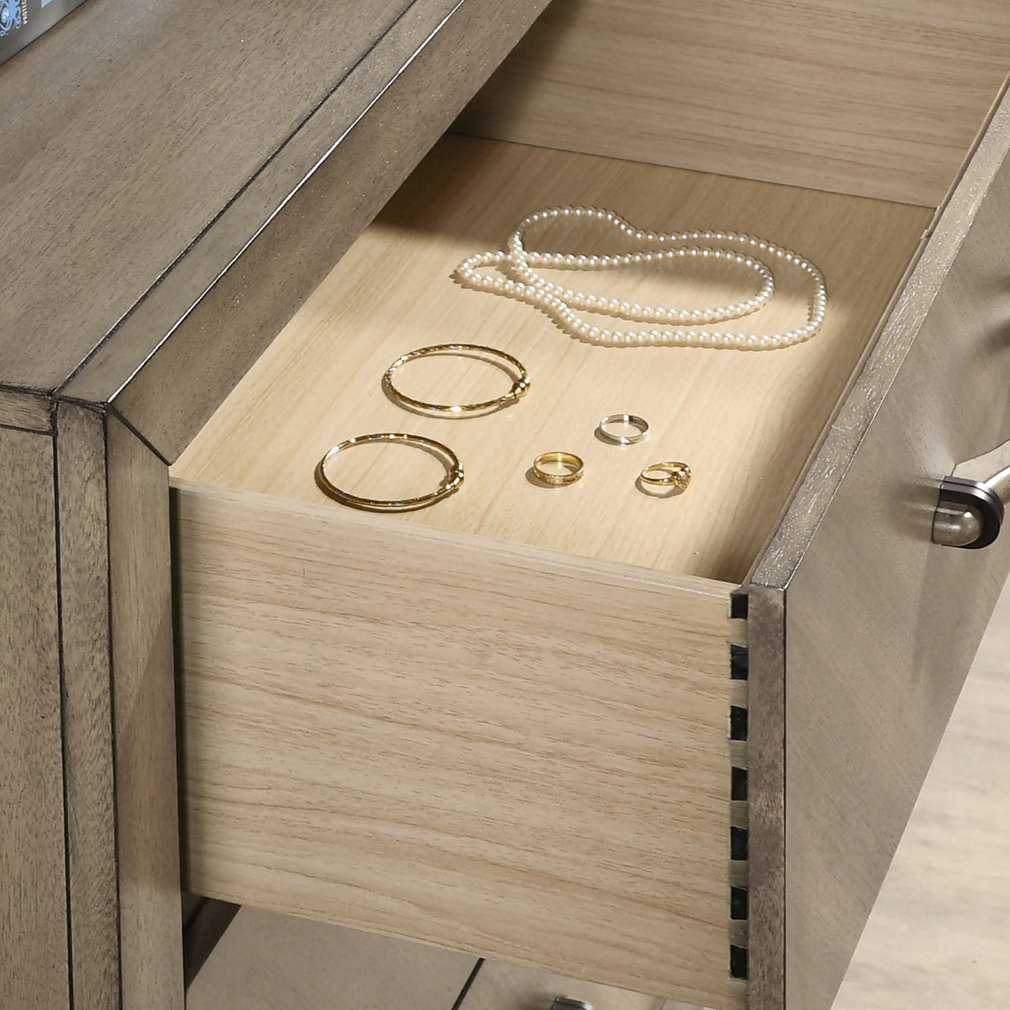 Gold and silver rings and pearl necklace arranged on a light wood jewelry organizer