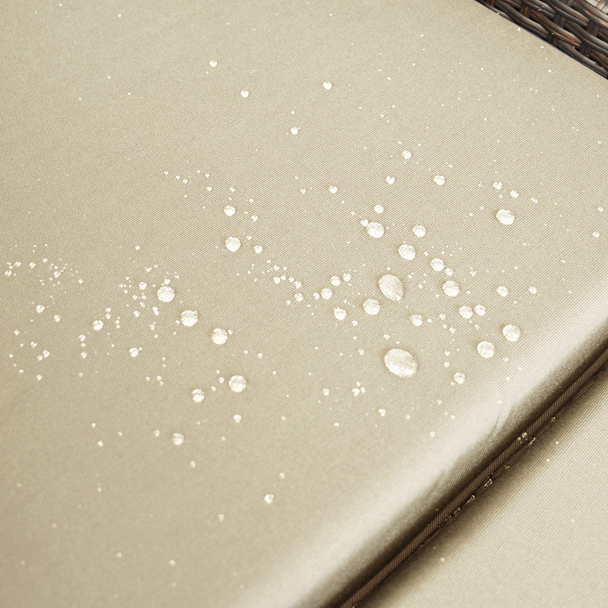 Beige outdoor cushion fabric with visible water droplets showcasing its waterrepellent quality
