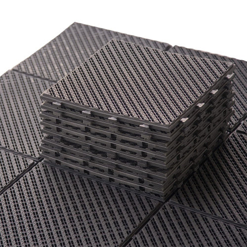 Stack of black interlocking drainage tiles with a diamond pattern surface
