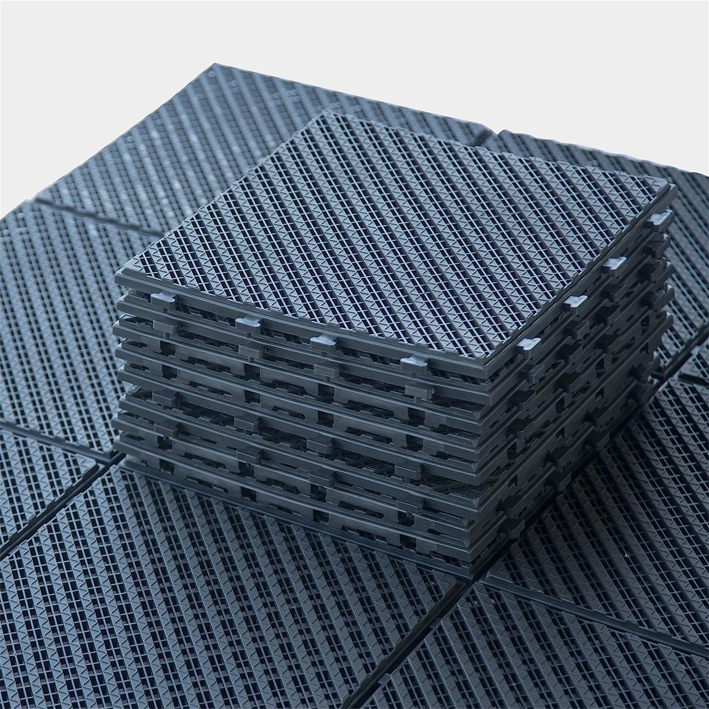 Stack of interlocking dark gray plastic garage floor tiles with textured surface