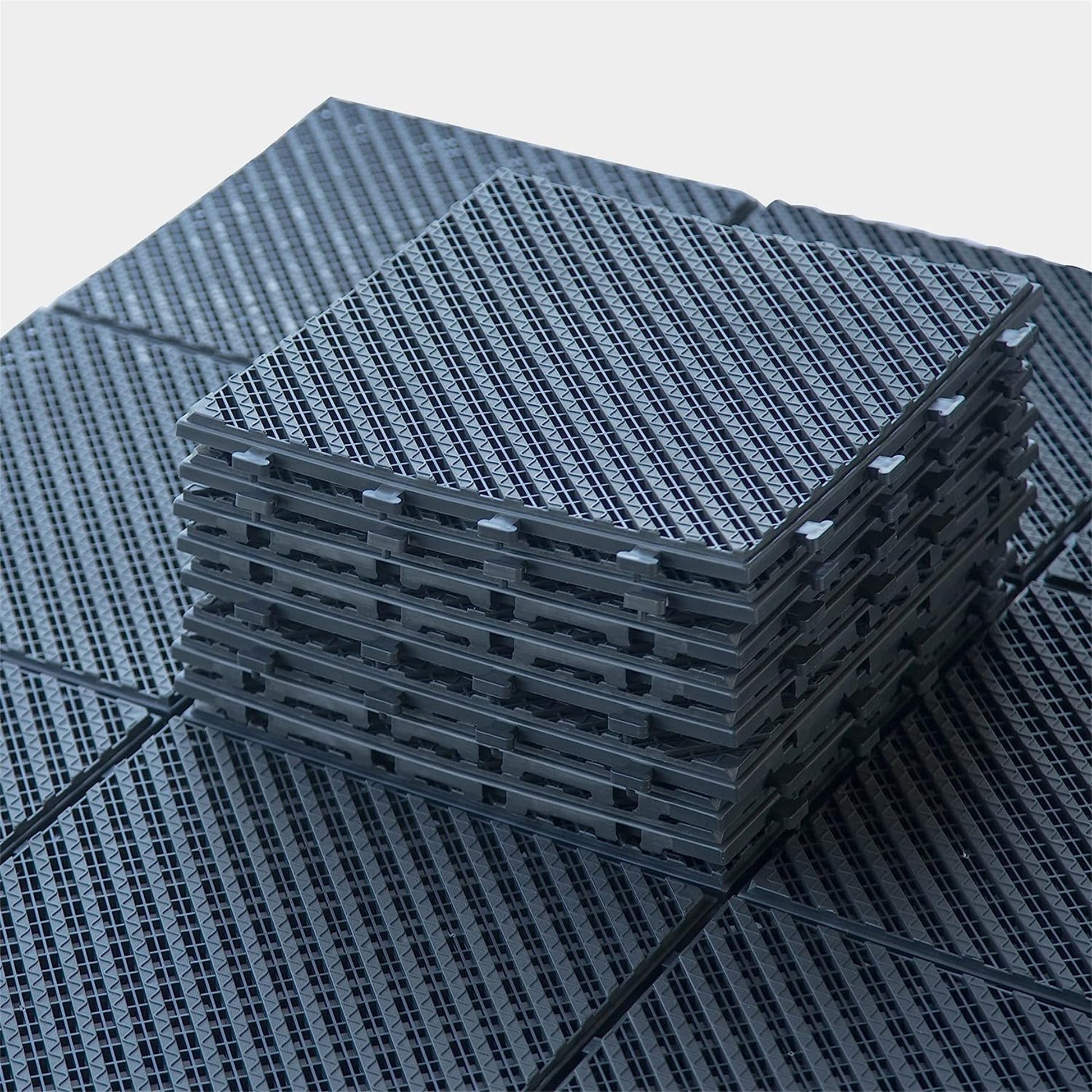 Stack of interlocking dark gray plastic garage floor tiles with textured surface