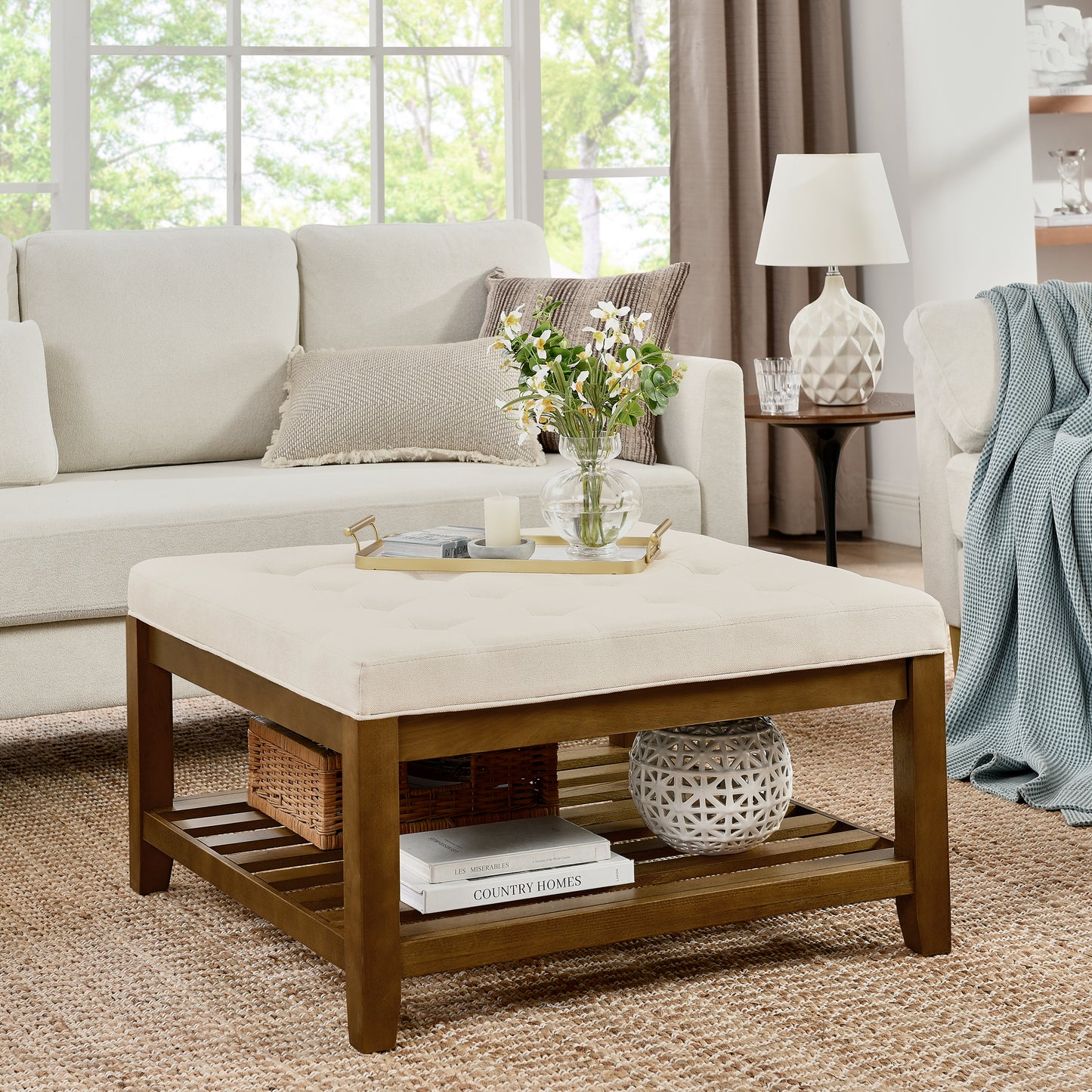 Tufted cream fabric storage ottoman with wooden frame and open shelf ideal for living rooms
