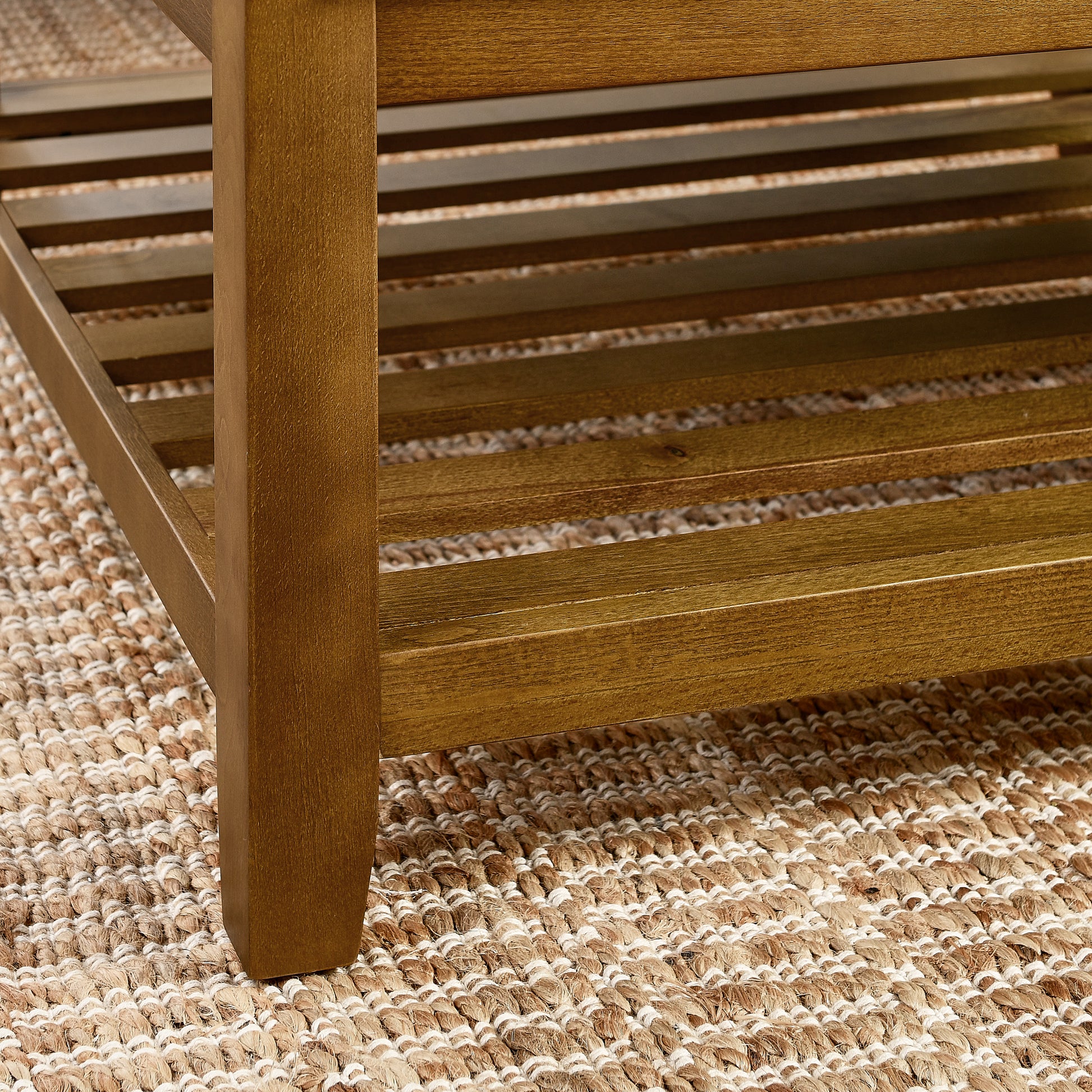 Natural wood coffee table leg with slatted shelf detail on woven rug