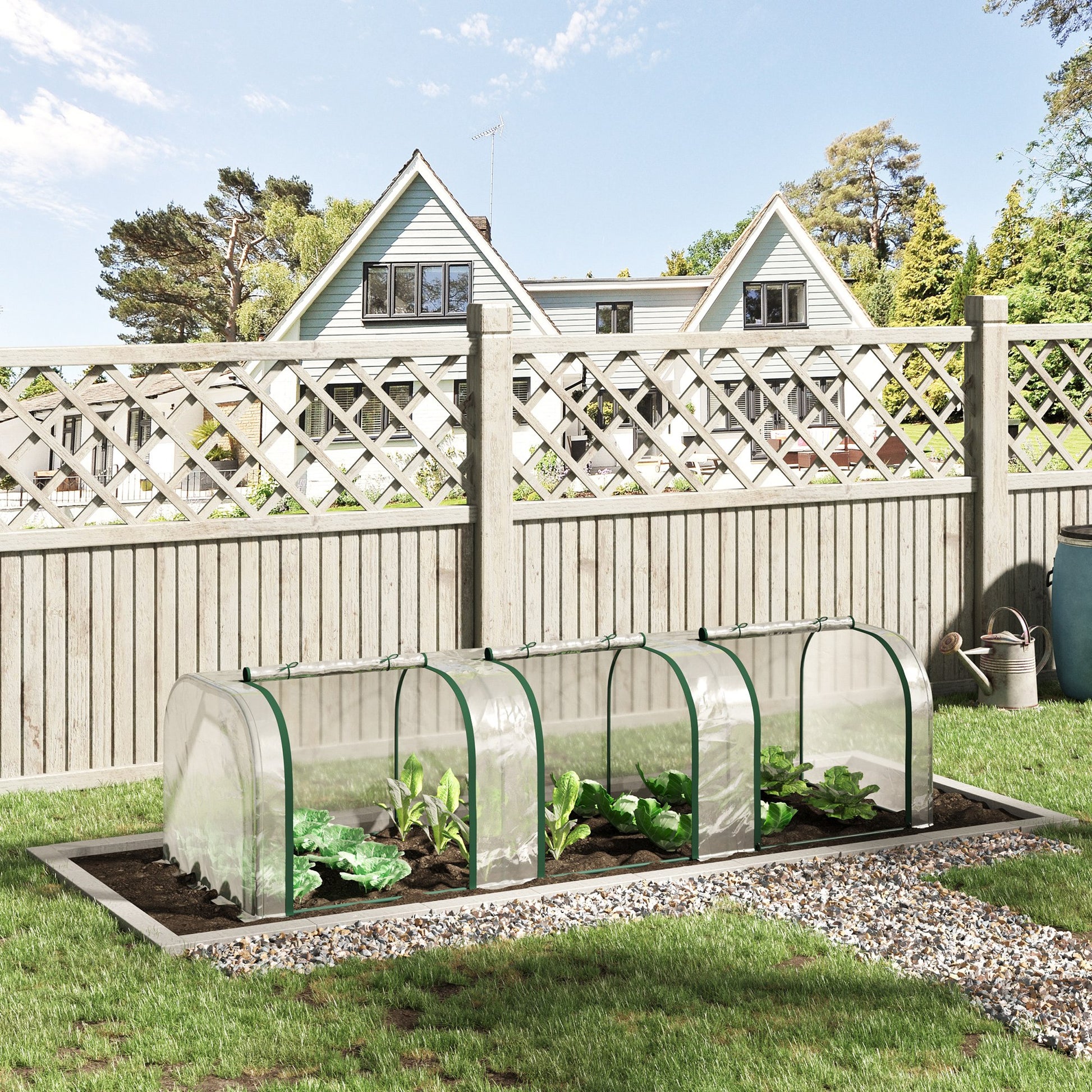 Clear mini greenhouse with green trim protecting young cabbage plants set in a garden bed