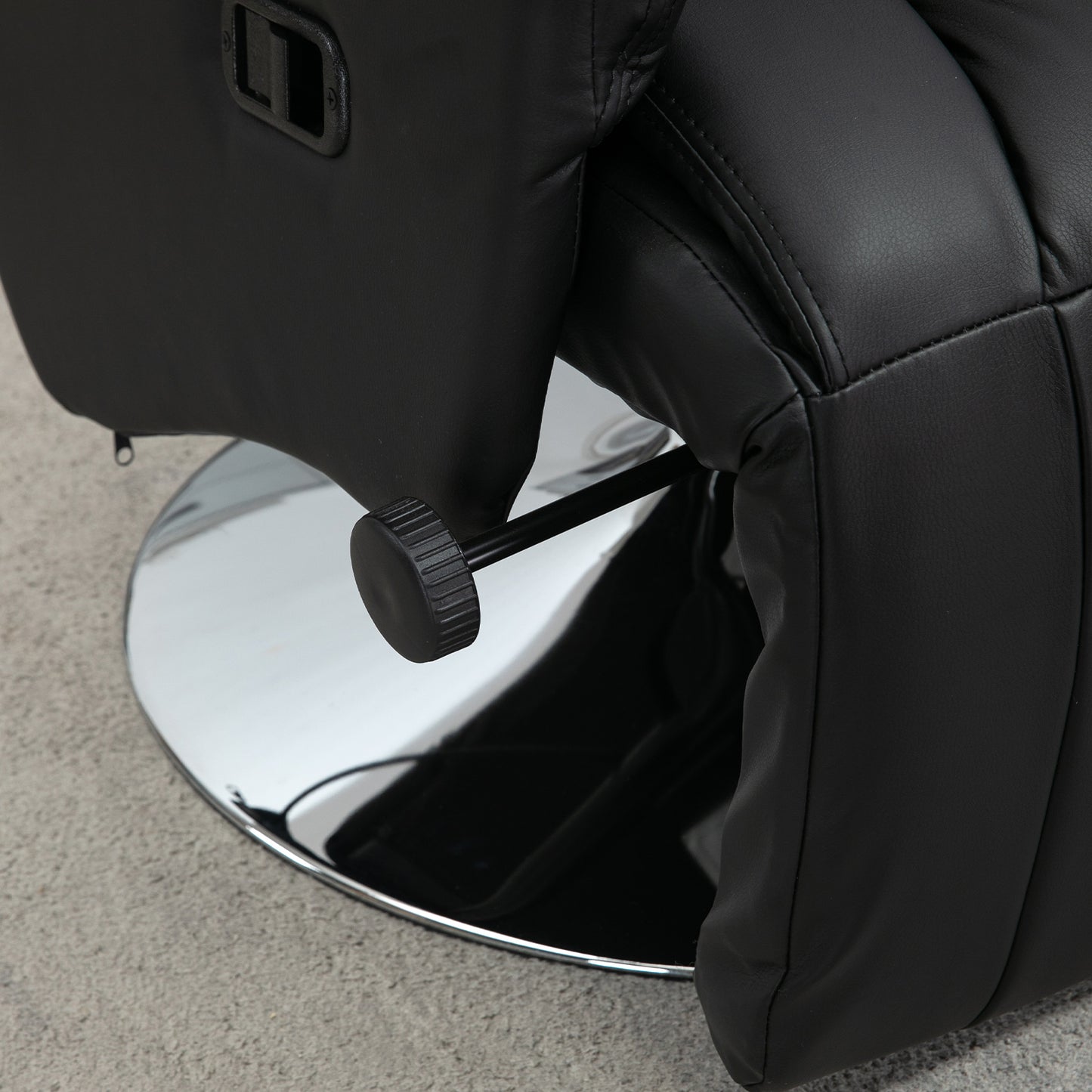 Black faux leather recliner chair detail with chrome swivel base and lever for reclining