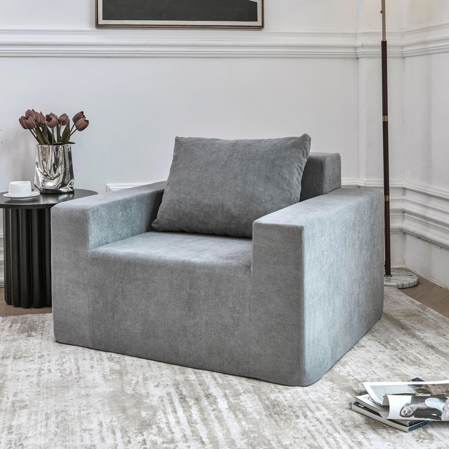 Plush gray armchair with a single square throw pillow ideal for a modern living room