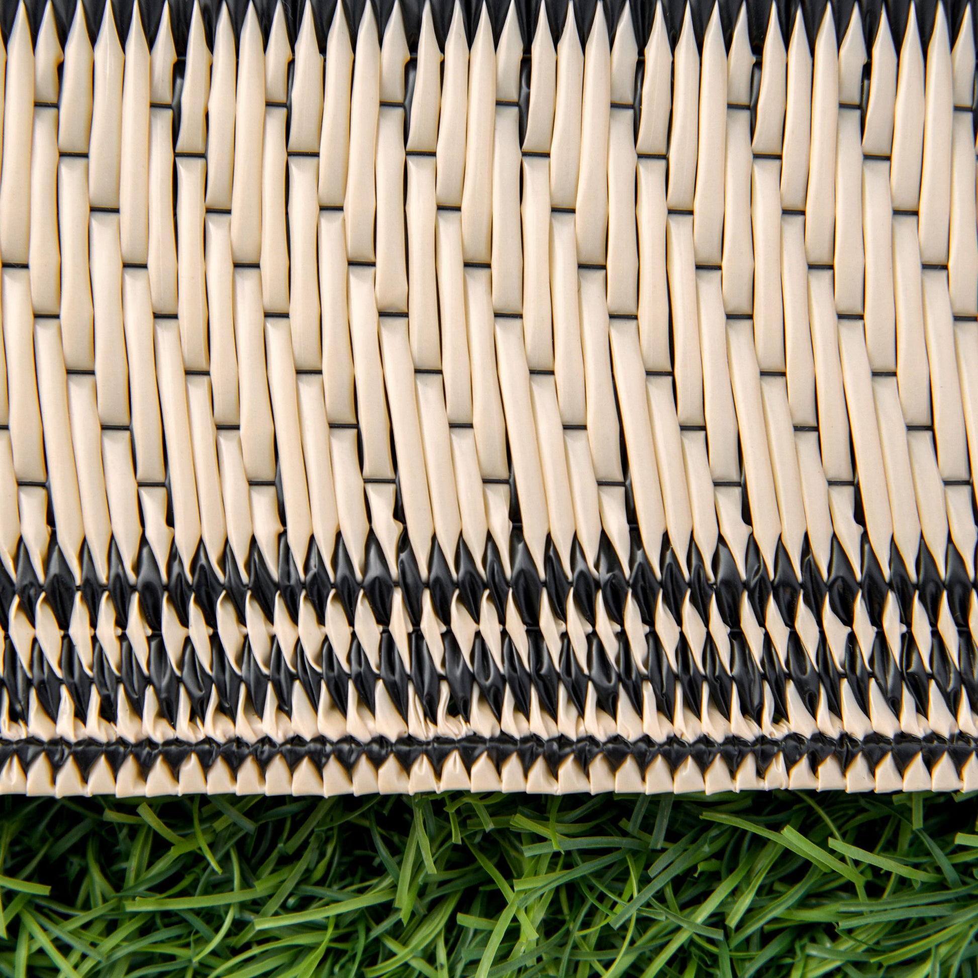 Woven beige and black striped basket weave texture on artificial grass