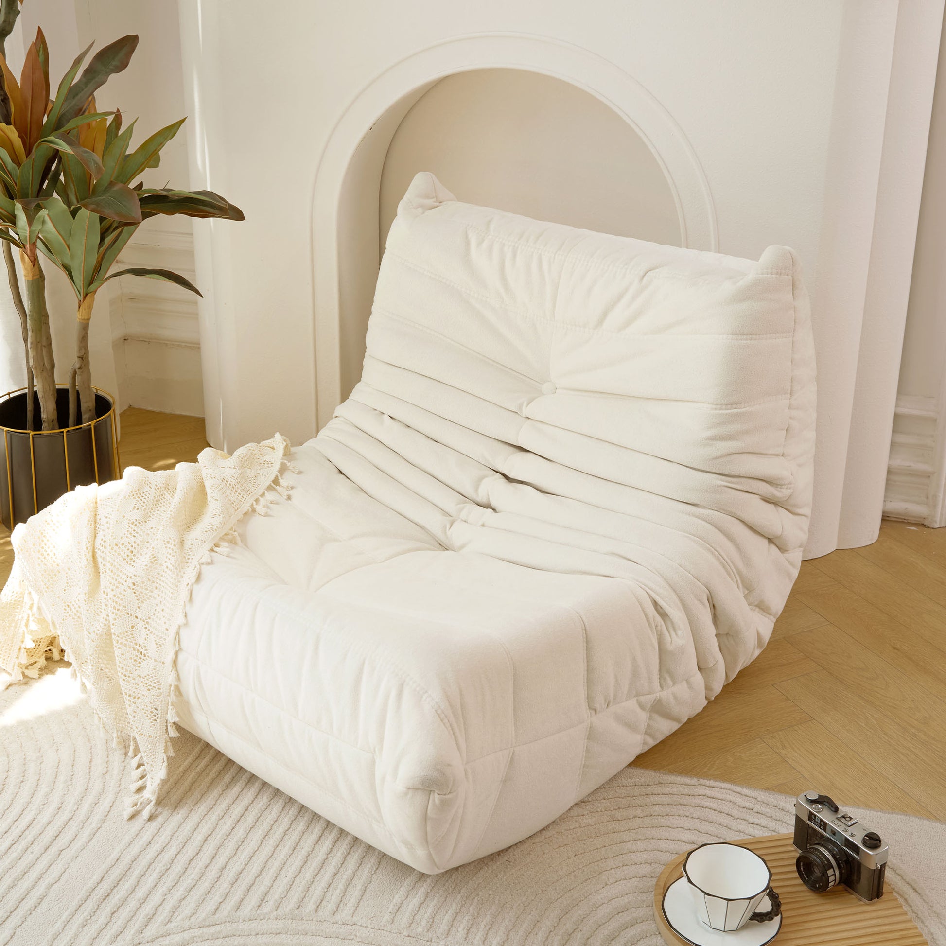 Plush cream Togo sofa with deep channel tufting and button accent perfect for modern living rooms