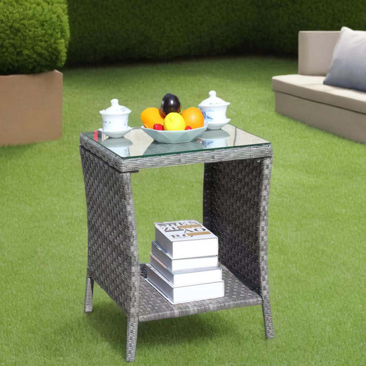 Grey wicker outdoor side table with glass top fruit bowl and books