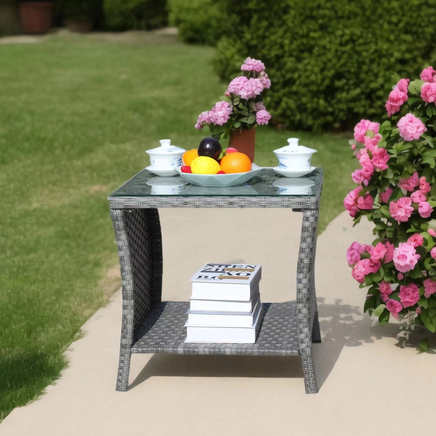 Gray wicker patio side table with glass top fruit and books