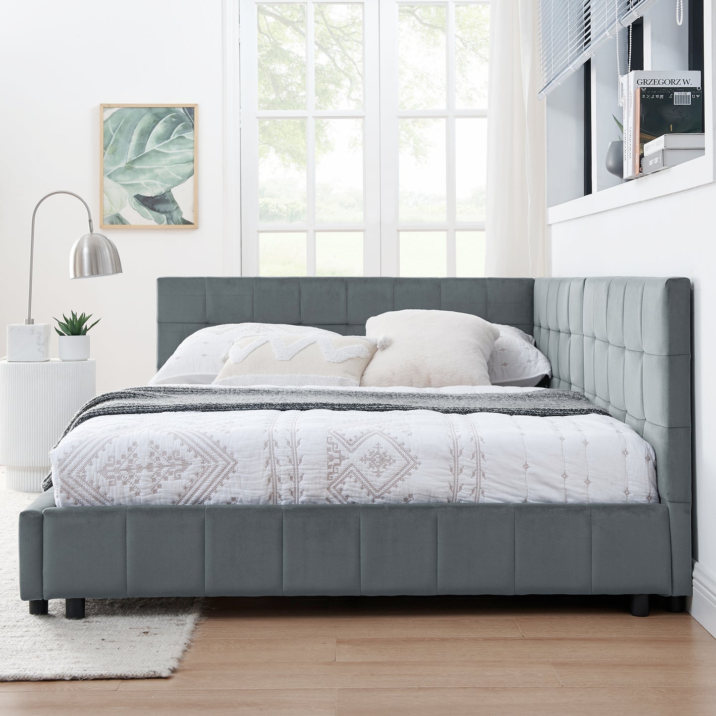 Grey upholstered platform bed with tufted headboard and a white patterned duvet