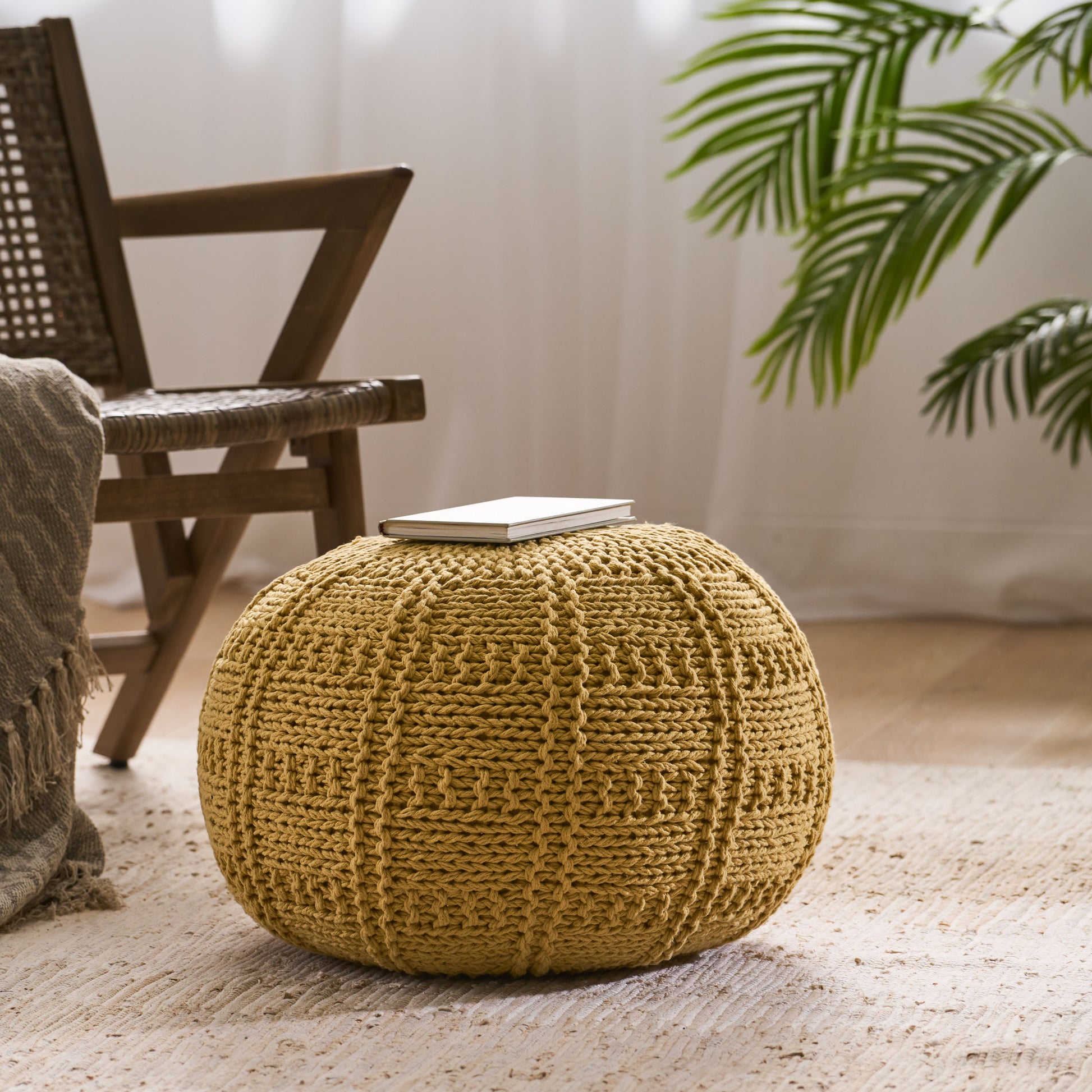 Round mustard yellow knitted pouf with textured pattern perfect as a footrest