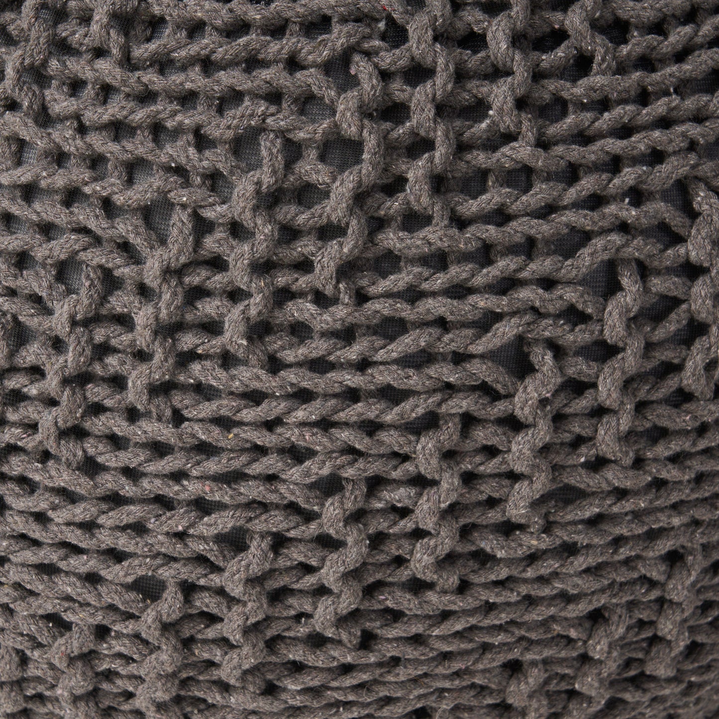 Closeup of a textured dark grey knitted throw pillow with chunky yarn