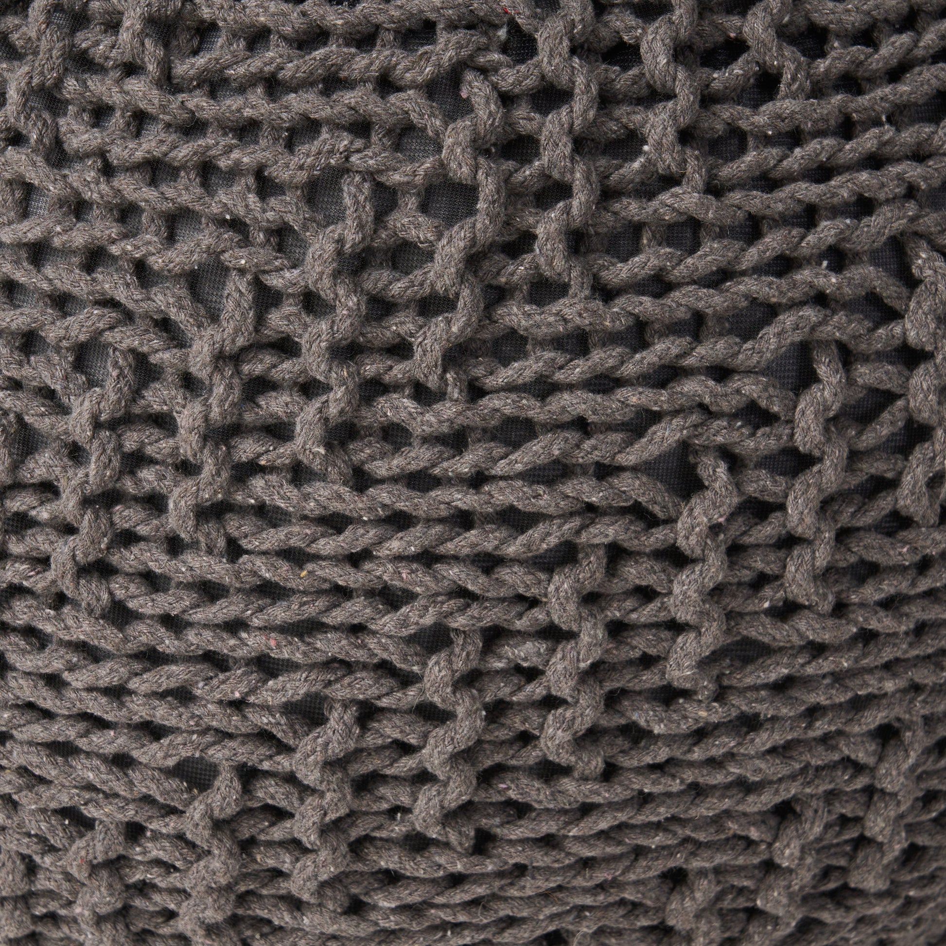 Closeup of a textured dark grey knitted throw pillow with chunky yarn