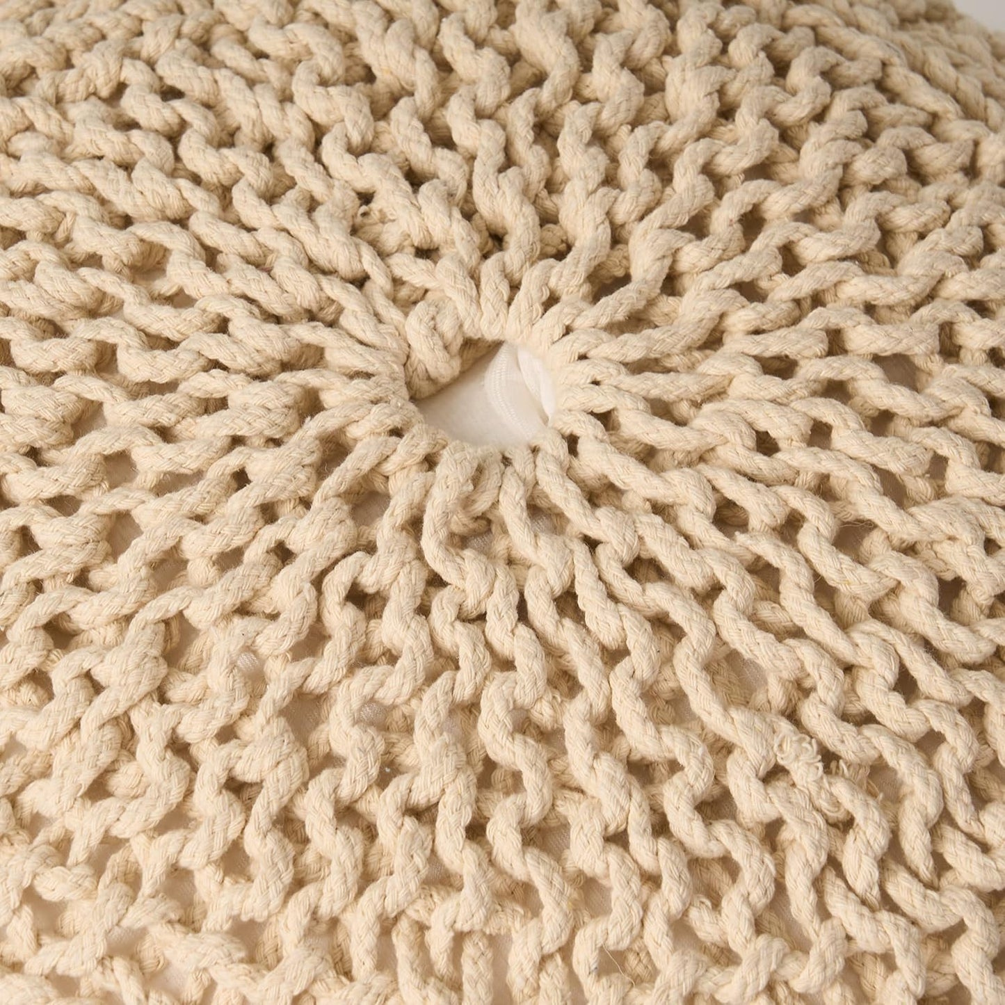 Closeup of a creamcolored chunky knit pouf showcasing textured yarn loops for bohemian decor