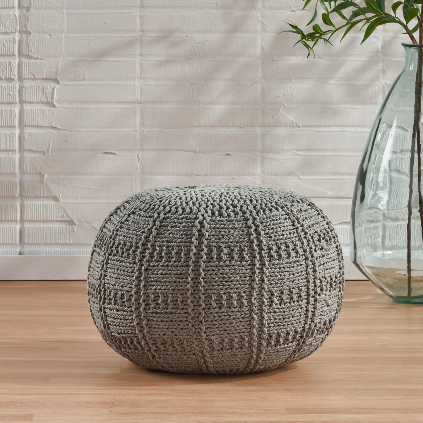 Textured gray knit pouf with intricate stitch pattern perfect for footrest or accent seating