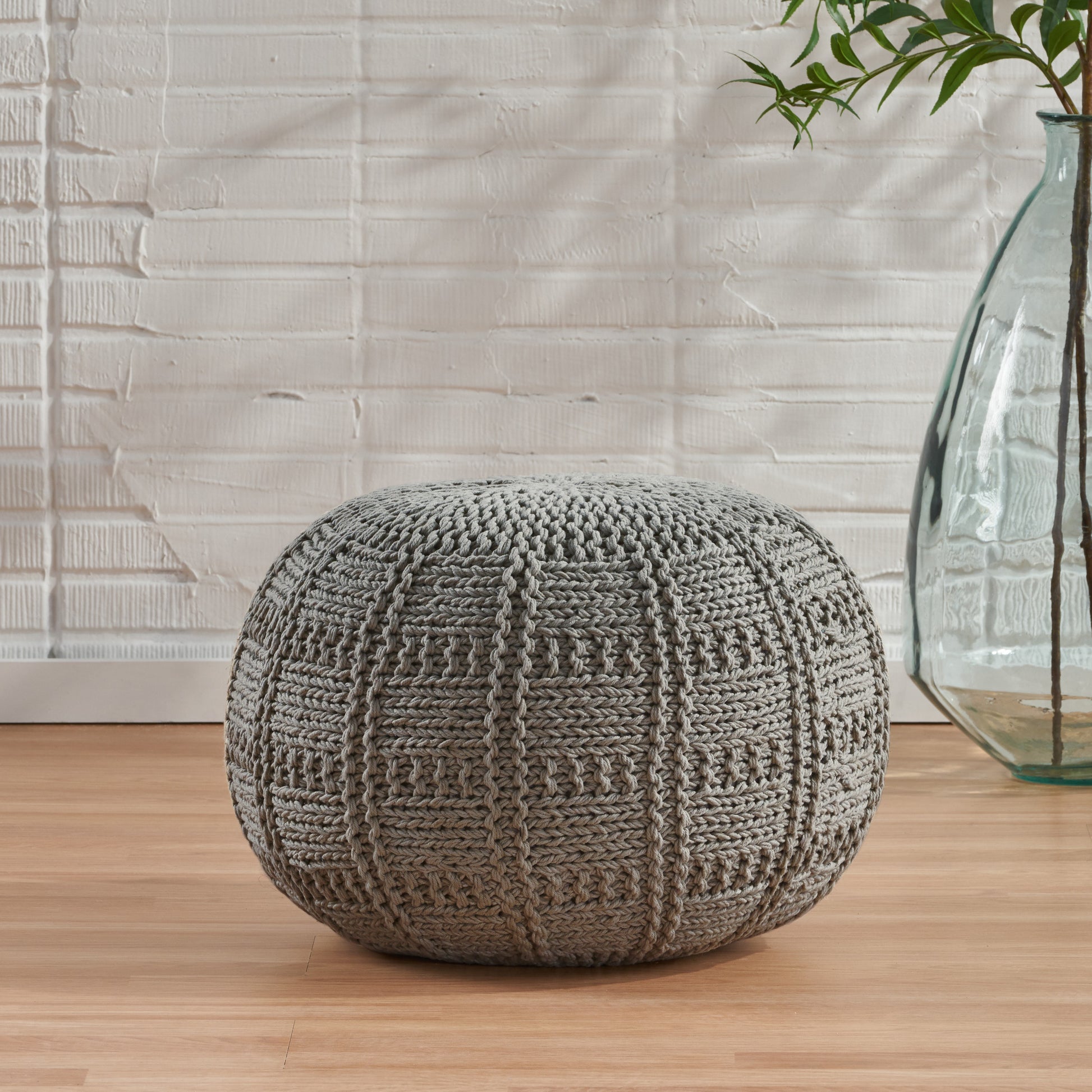 Textured gray knit pouf with intricate stitch pattern perfect for footrest or accent seating