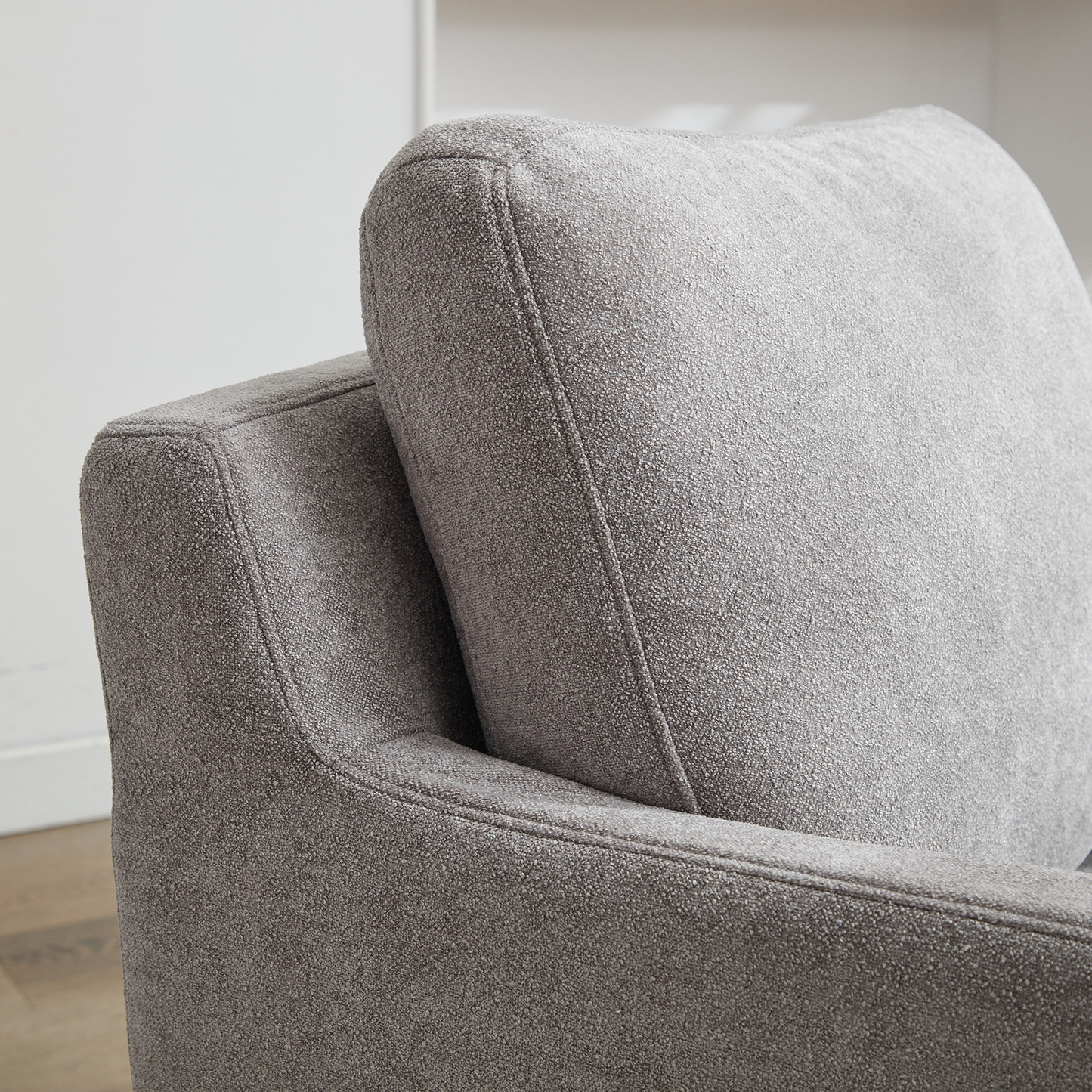 Closeup of textured grey fabric on a modern armchair with detailed stitching