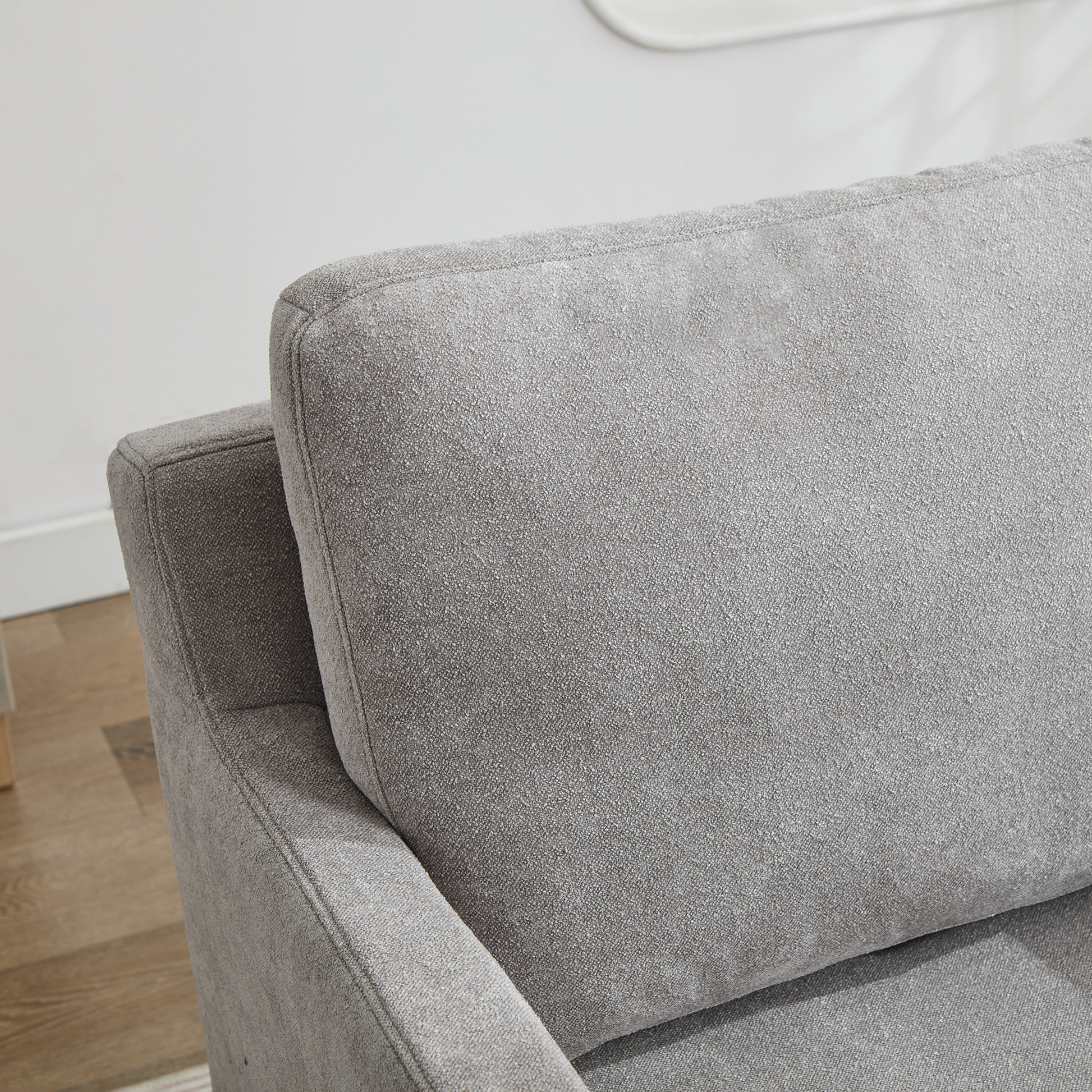 Close up of a textured grey fabric sofa with visible stitching details