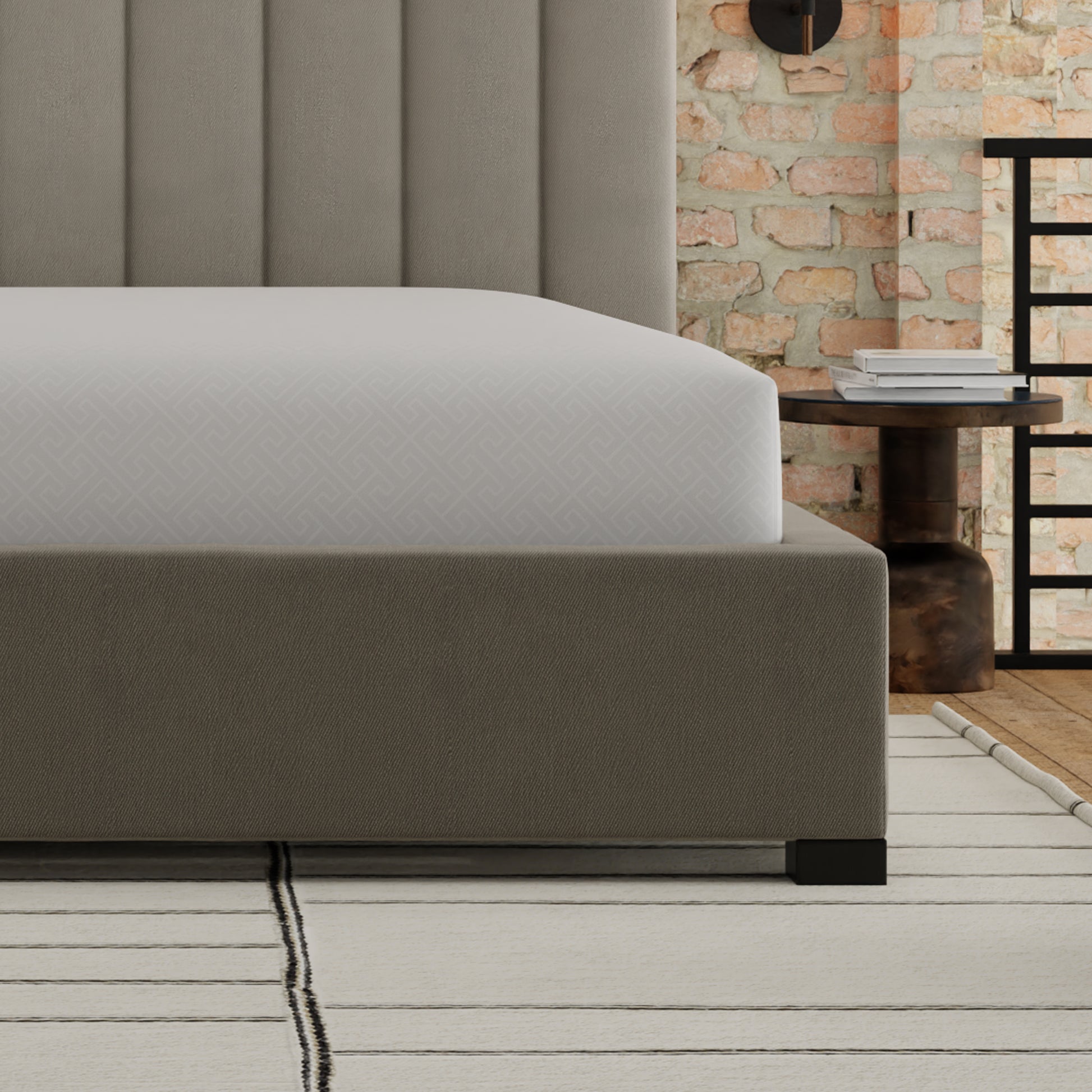 Upholstered king size bed frame in taupe with a channel tufted headboard and grey patterned fitted sheet