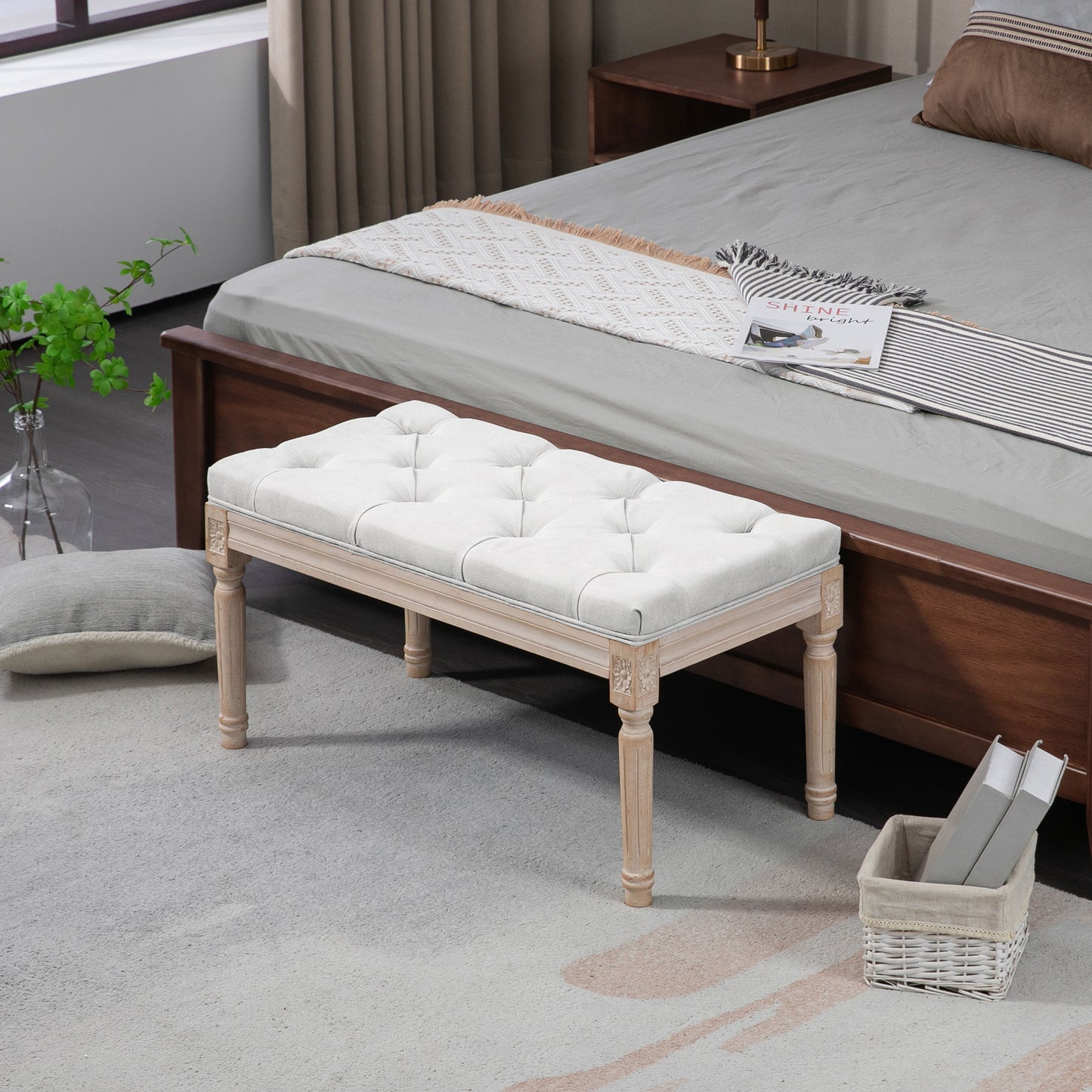 Tufted white linen bench with carved light wood legs perfect for a bedroom accent