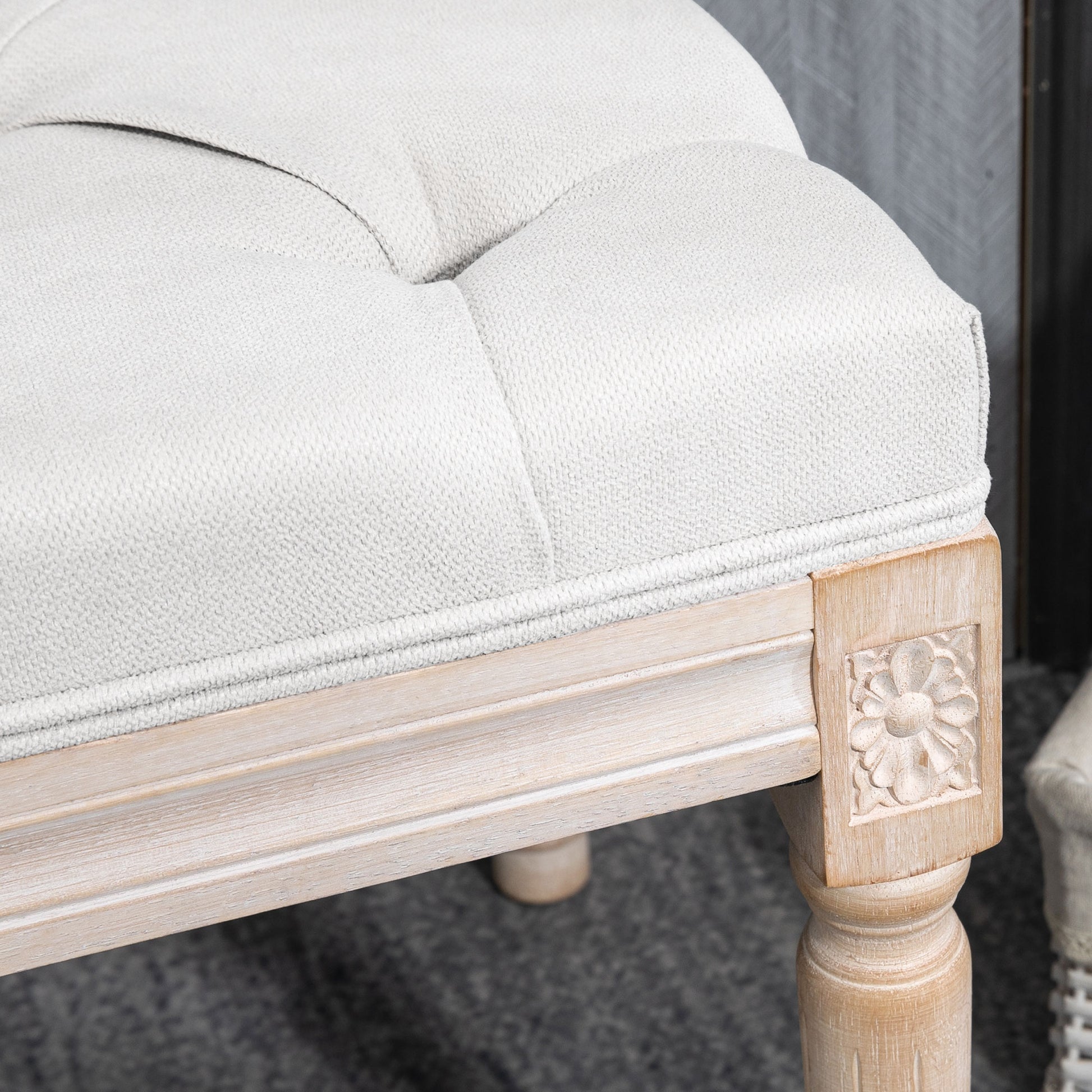 White linen tufted ottoman with distressed wood legs and floral carving